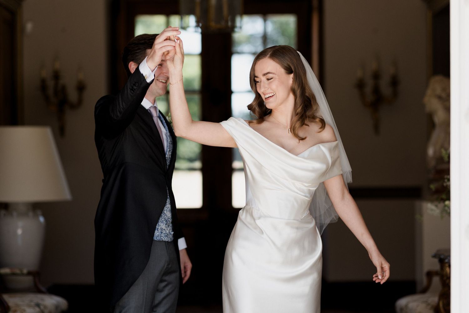 A couple dances together during their first dance at an elegant wedding reception in a bright indoor venue.