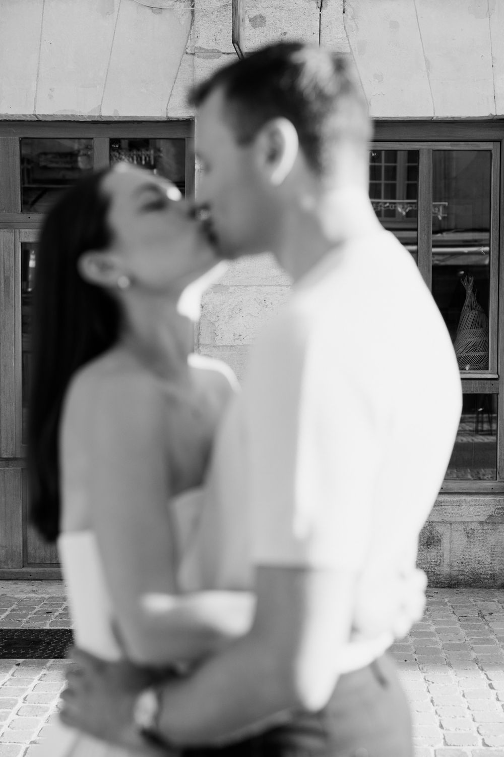 A black and white photo sequence showing a couple embracing and kissing in front of a building facade.