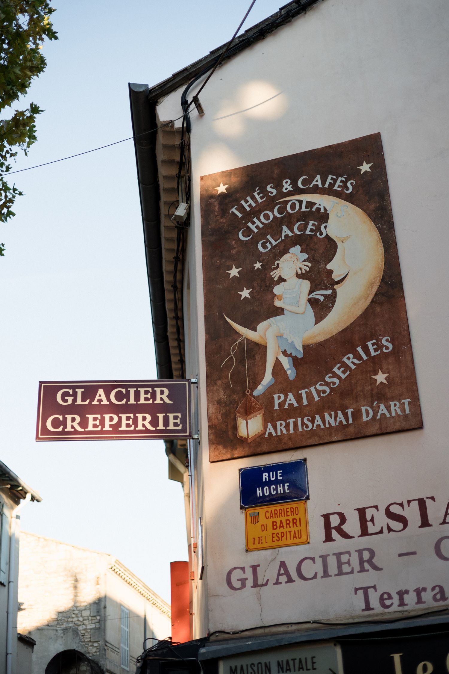 Vintage-style French cafe and patisserie signs featuring whimsical moon motifs on rustic wooden boards. Engagement session Paris