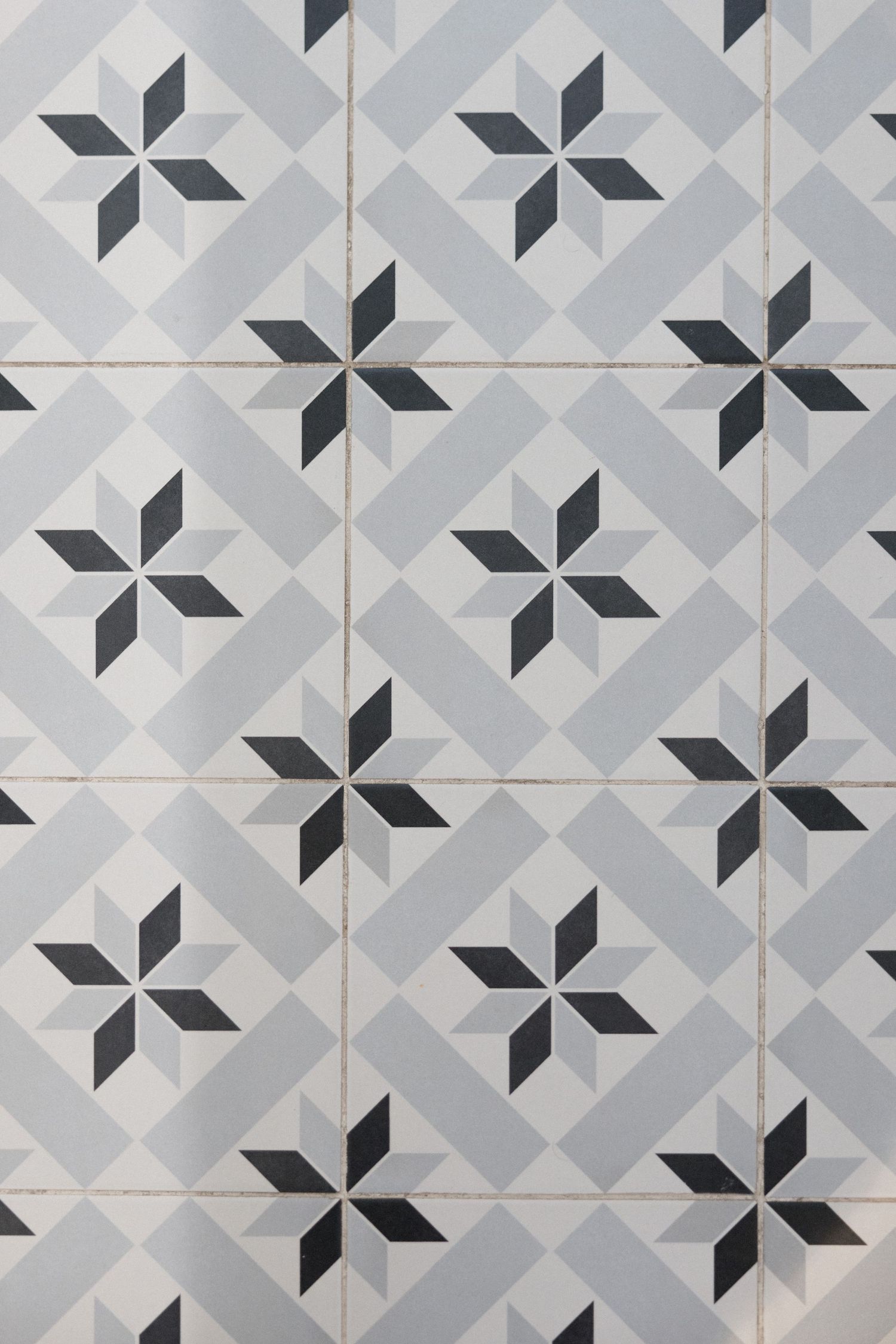 Gray and white geometric star pattern ceramic tiles with dark diamond accents arranged in a repeating grid design.