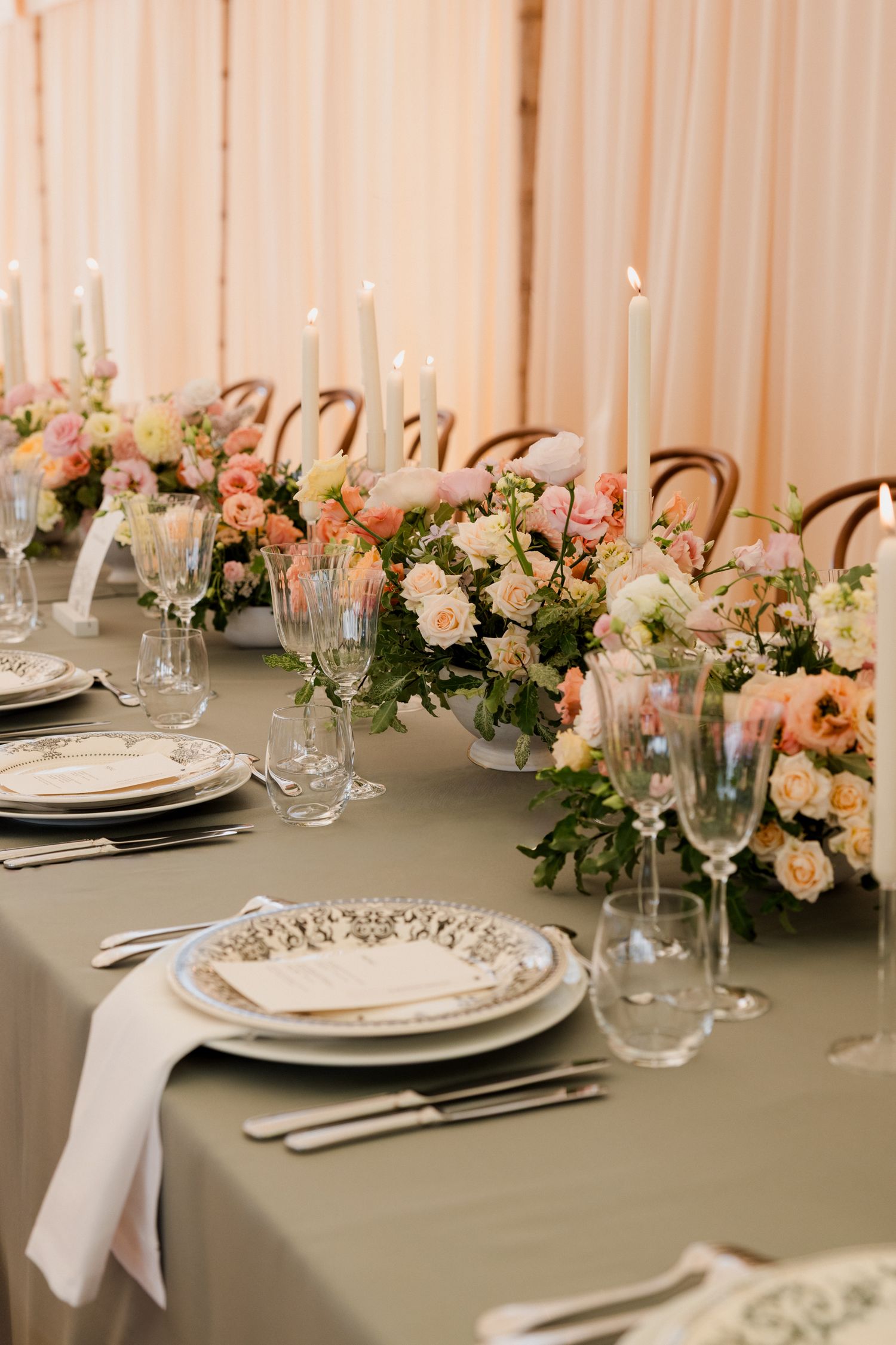 Elegant wedding table setting with white candles, blush floral centerpieces and place settings on a sage green tablecloth. Paris wedding pho