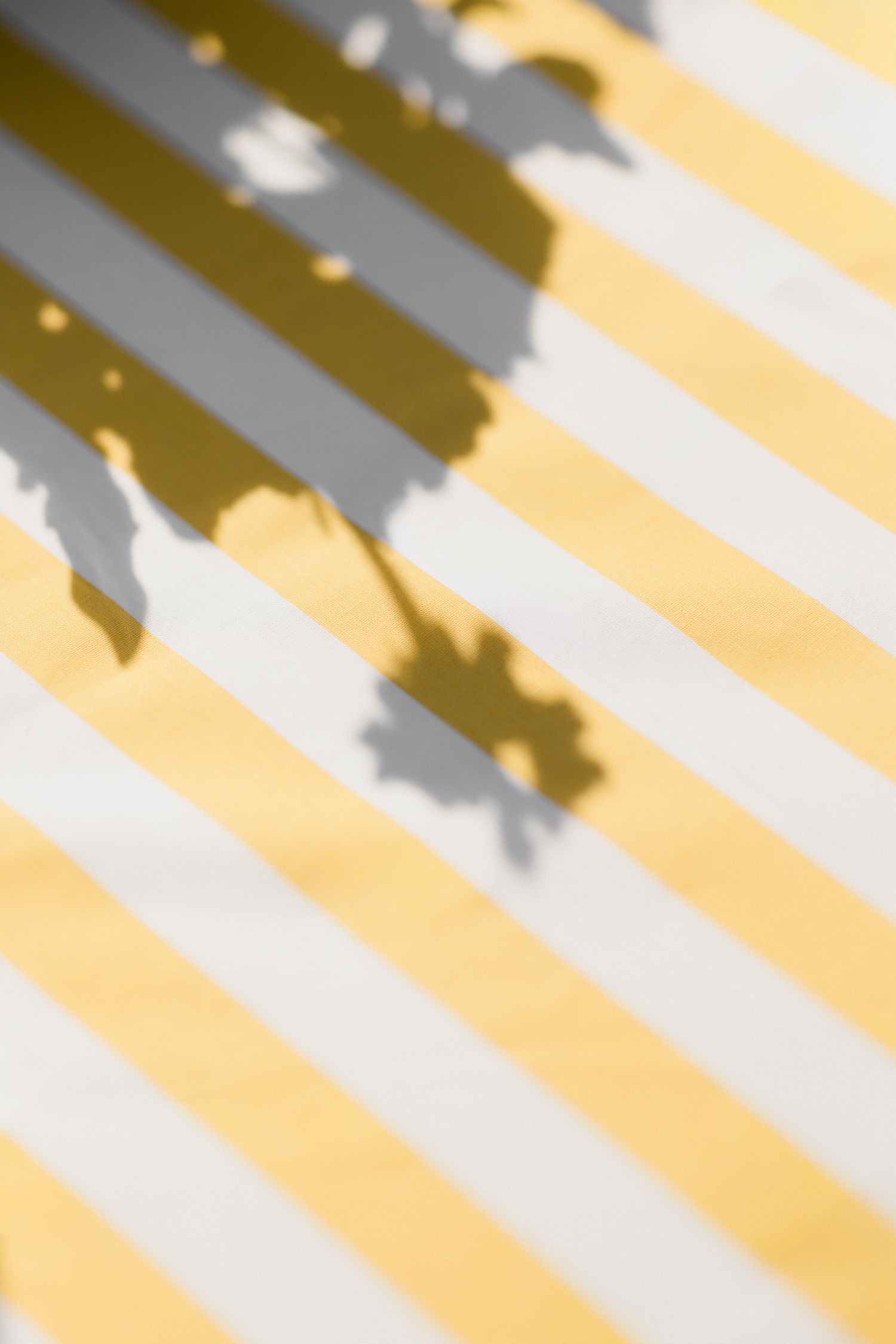 Diagonal yellow and gray stripes create an abstract geometric pattern with light and shadow effects.