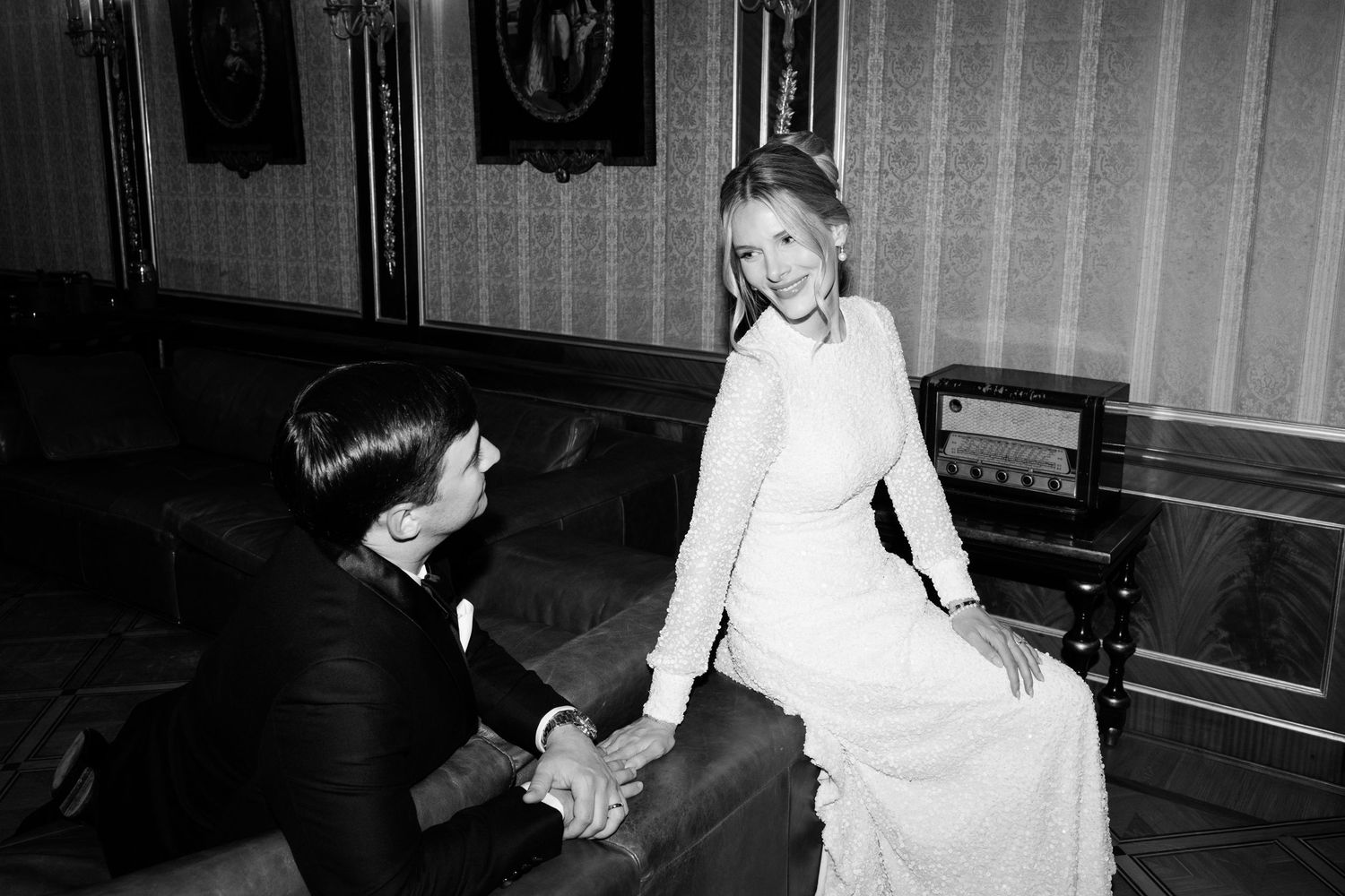 A vintage black and white photograph showing a romantic proposal moment with a white dress and kneeling figure. luxe wedding france