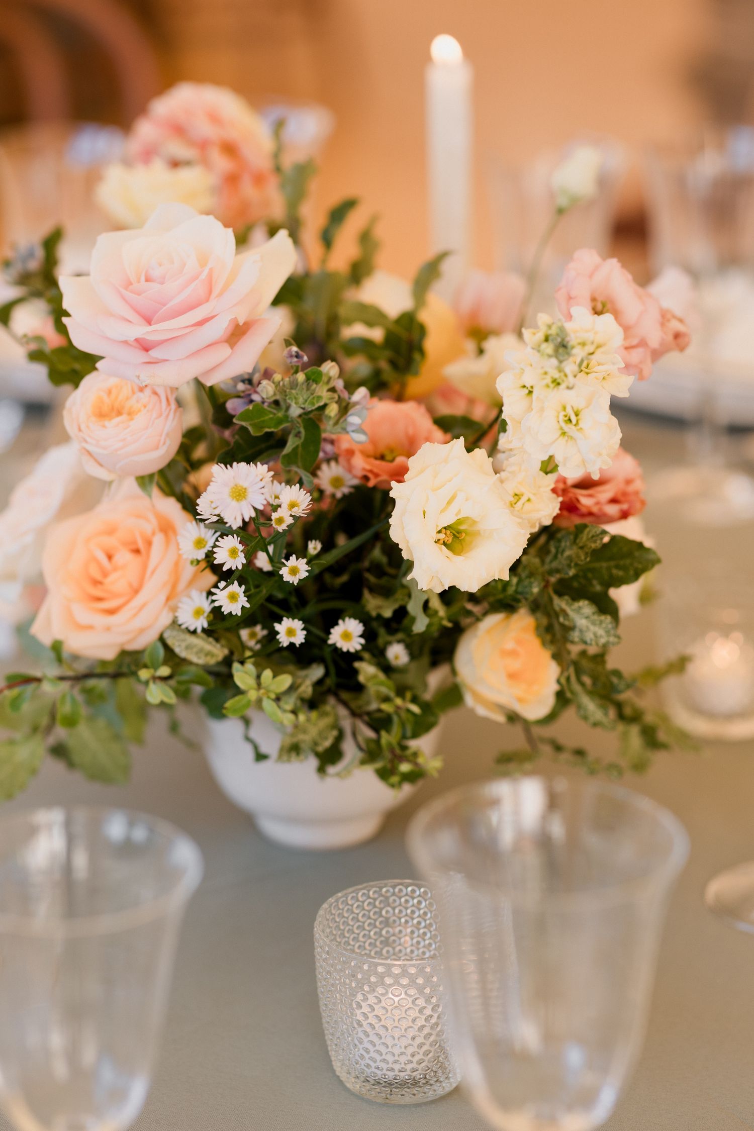 Elegant floral centerpieces with pink and peach roses in crystal vases arranged on a wedding reception table. Paris wedding photographer