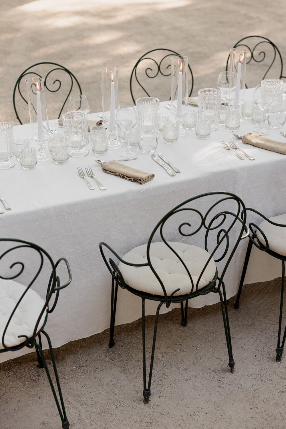 Elegant table setting with white linens and wrought iron chairs featuring scrolled backs and cushioned seats. Auberge de la Treille, Avignon