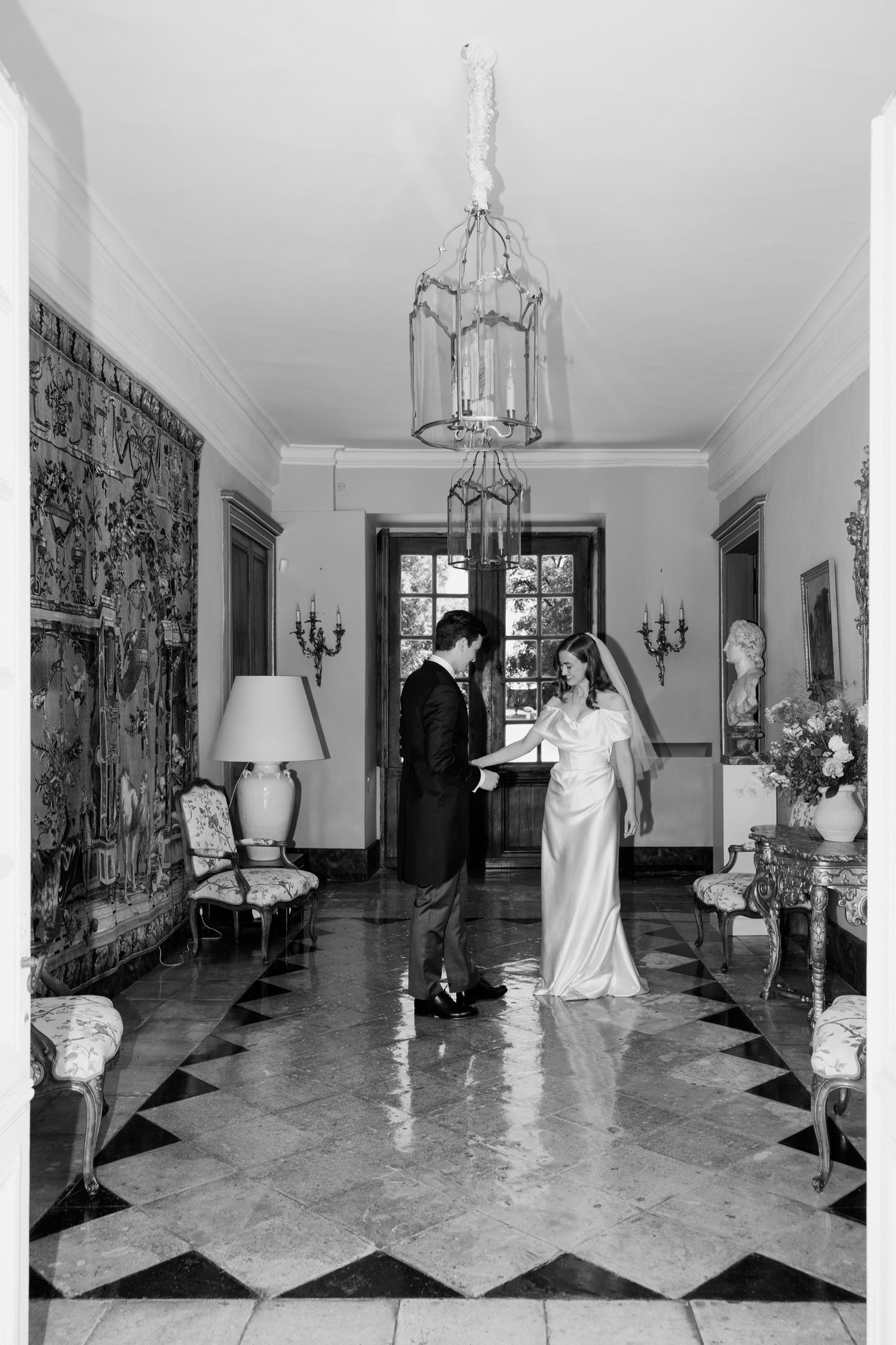 A black and white photo sequence showing figures in formal attire walking through an elegant marble-floored hallway.
