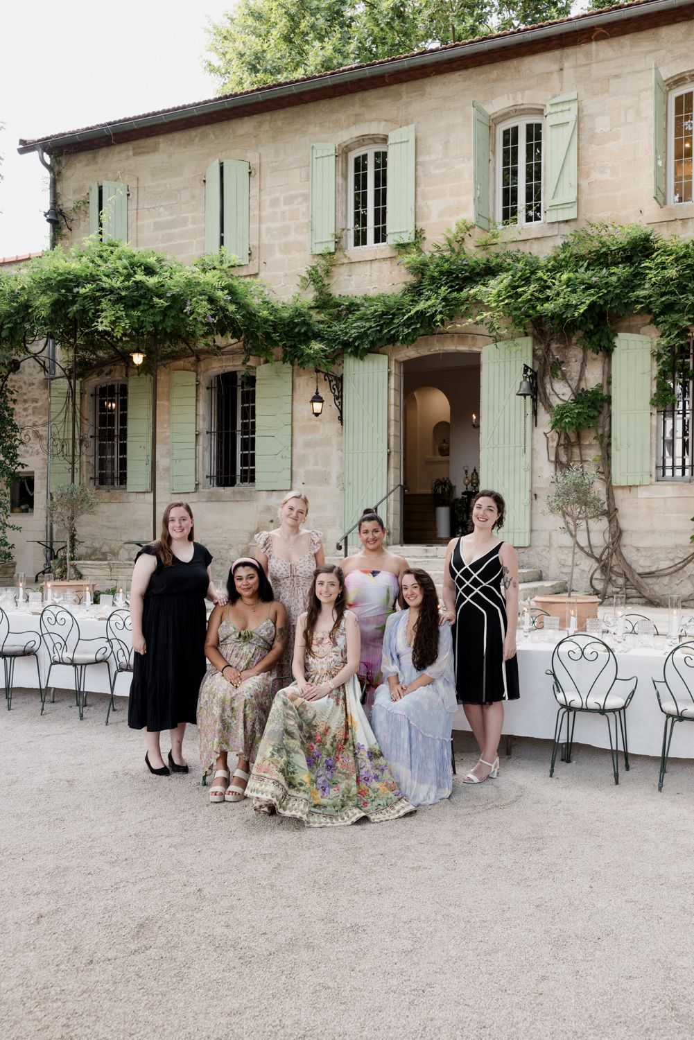 Elegant guests pose in front of a rustic French country house with climbing vines. Welcome Event Auberge de la Treille, Avignon