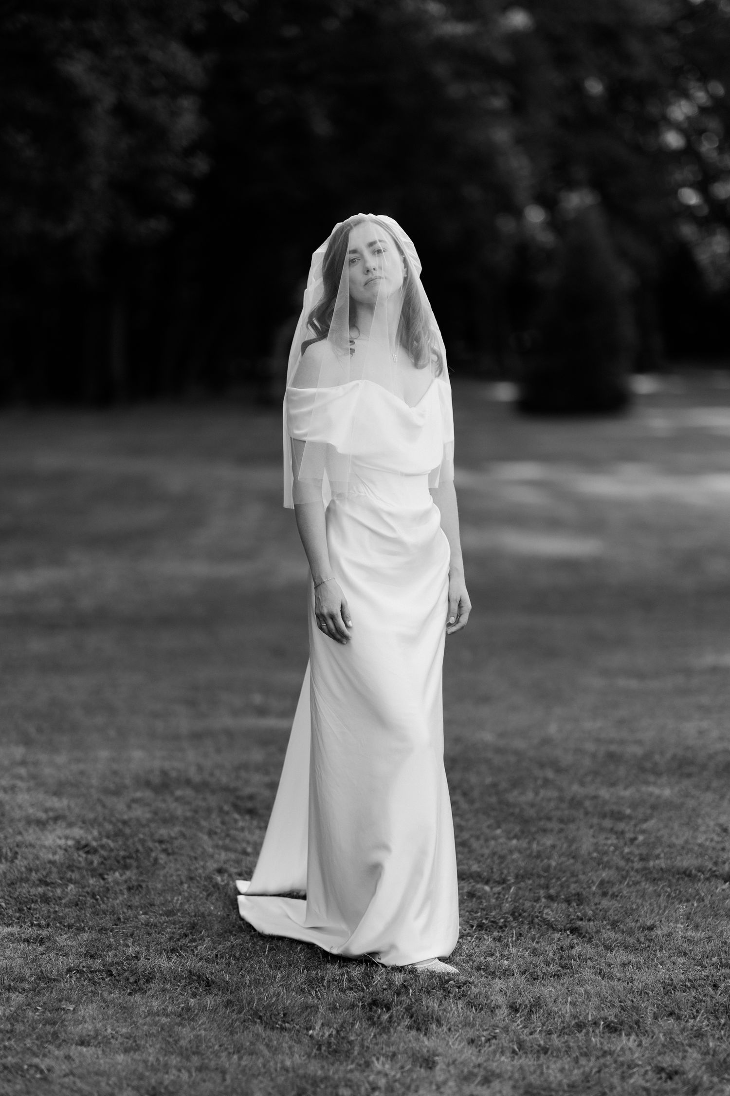 Black and white artistic sequence of a bride in a flowing white wedding dress standing in a grassy field. Luxury wedding france