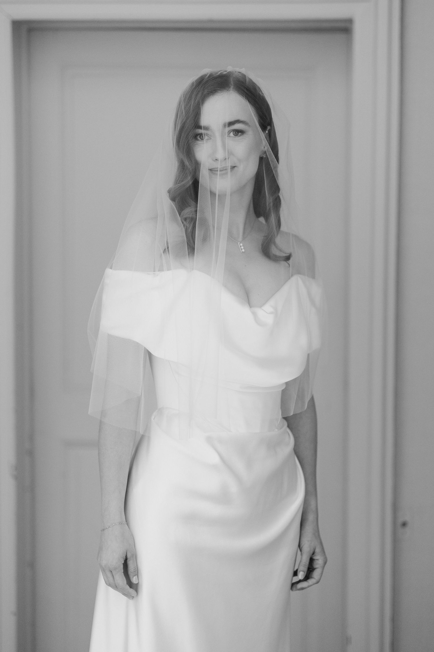 A black and white photo series showing a bride in a simple white dress and veil against a light background.
