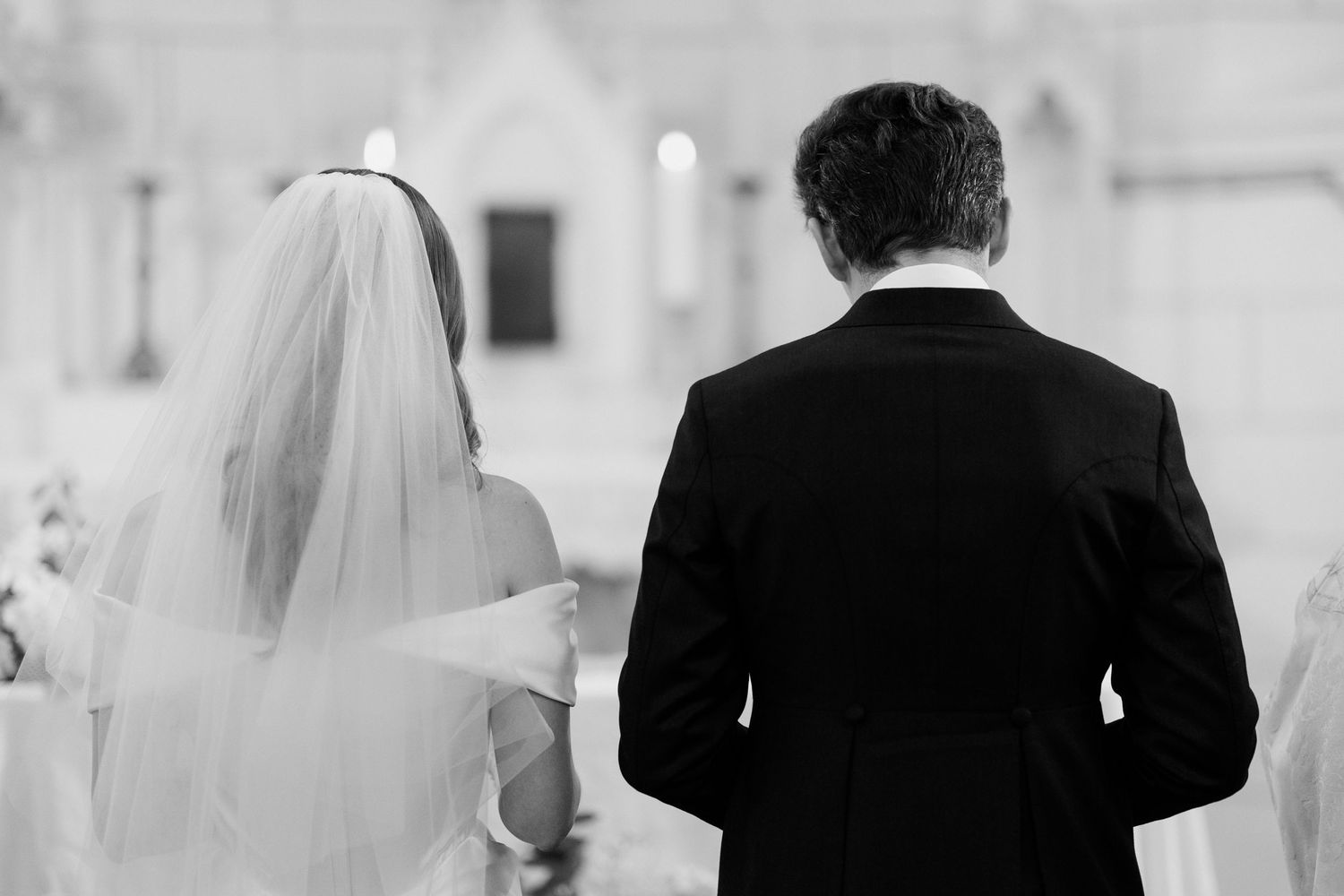 A bride and groom walk together in formal wedding attire with a soft blurred background. Paris wedding photographer