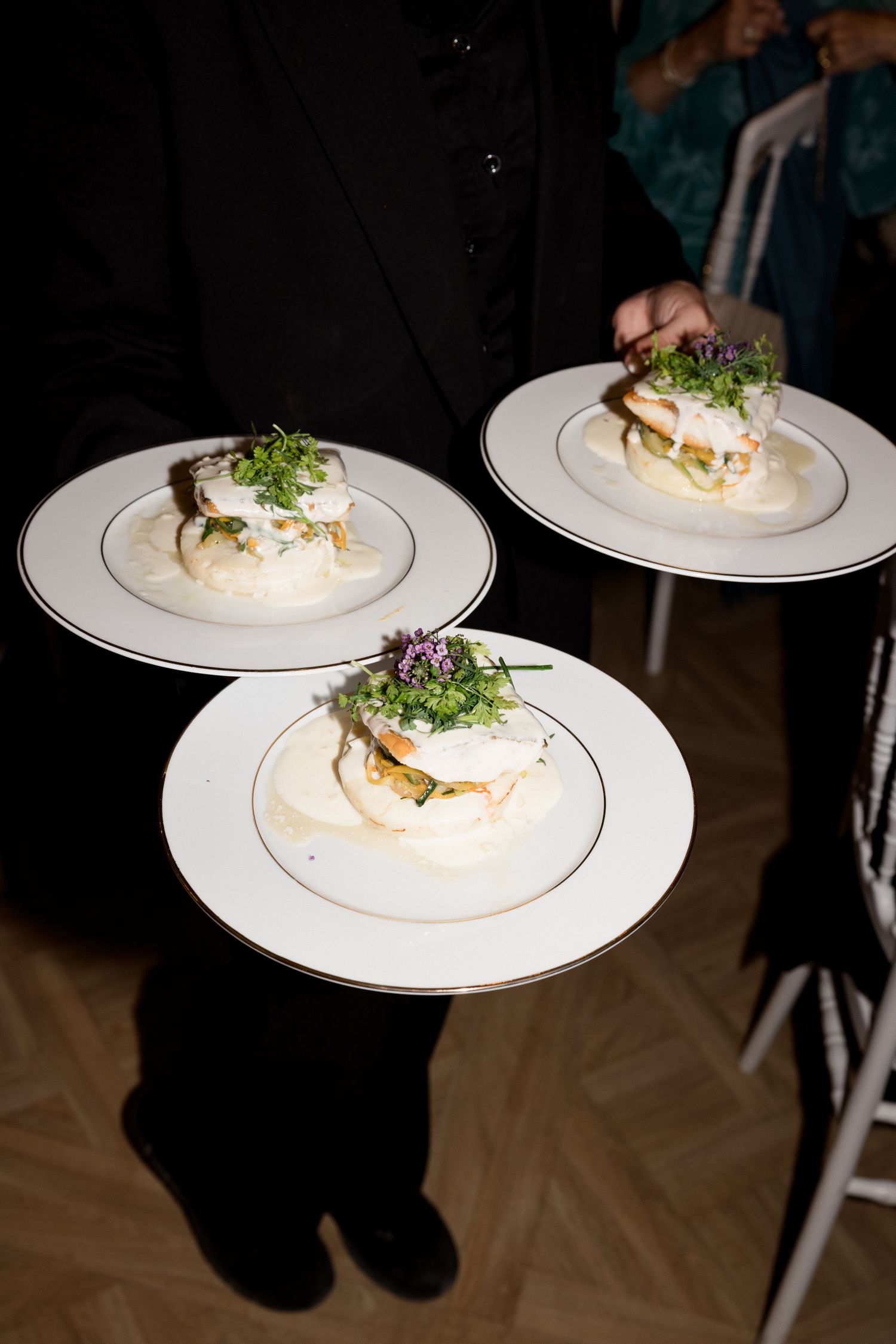A series of white plates displaying elegantly plated appetizers garnished with microgreens on a dark surface. De bouche en bouche traiteur