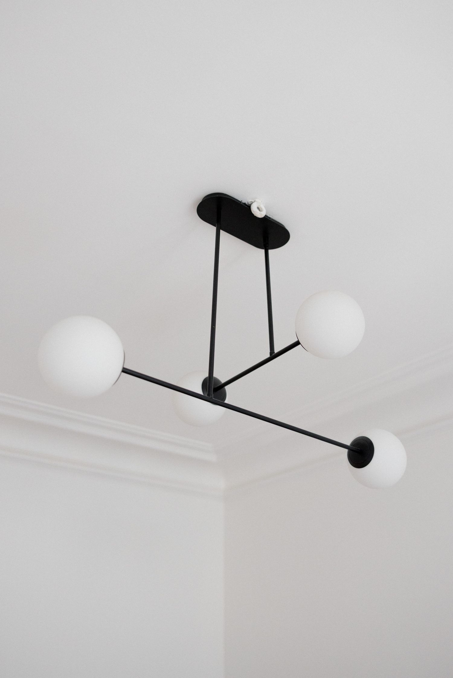 Modern black sputnik chandelier with three frosted globe shades mounted on white ceiling.