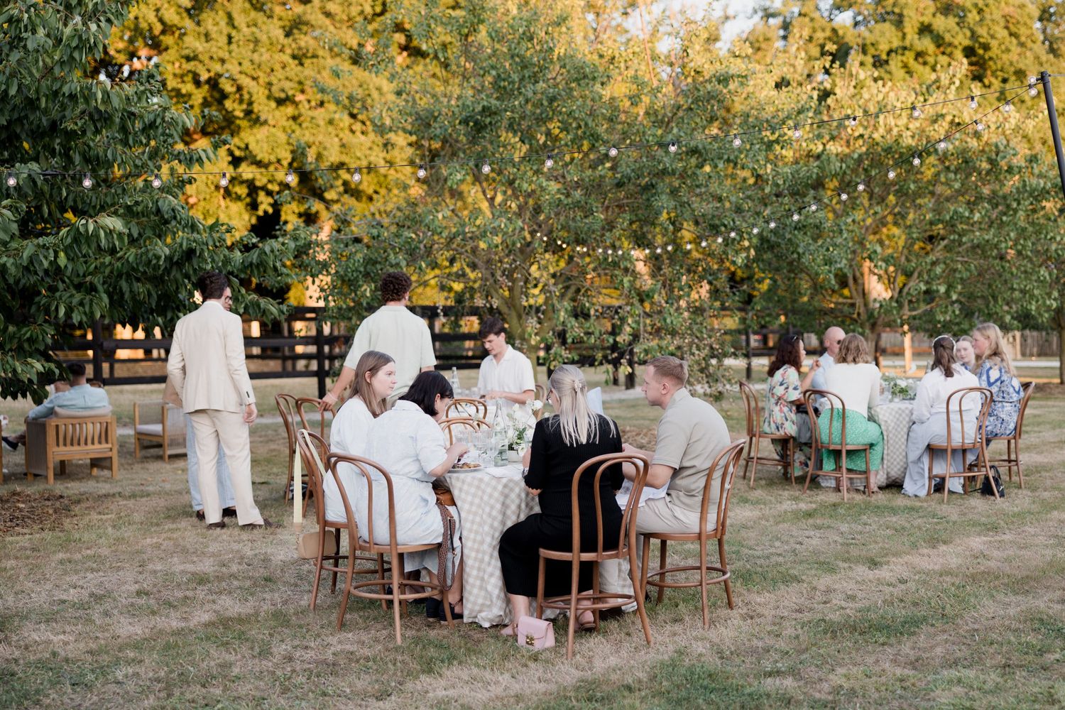 Outdoor wedding ceremony setup with white chairs arranged in rows under autumn trees during golden hour.