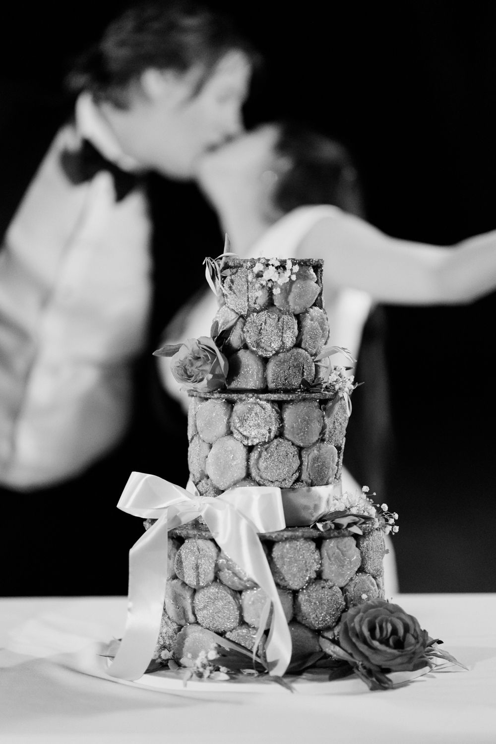 Stacked slices of artisanal nougat candy with dark rose garnish in dramatic black and white photography.