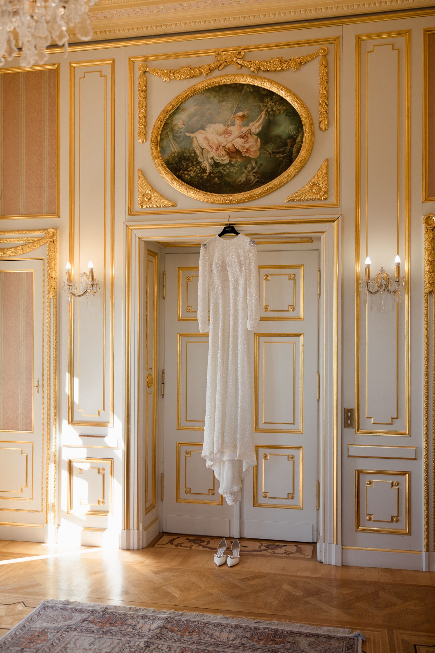 Elegant French palace interior with ornate gold trim, white paneled walls, hardwood floors and crystal chandeliers.