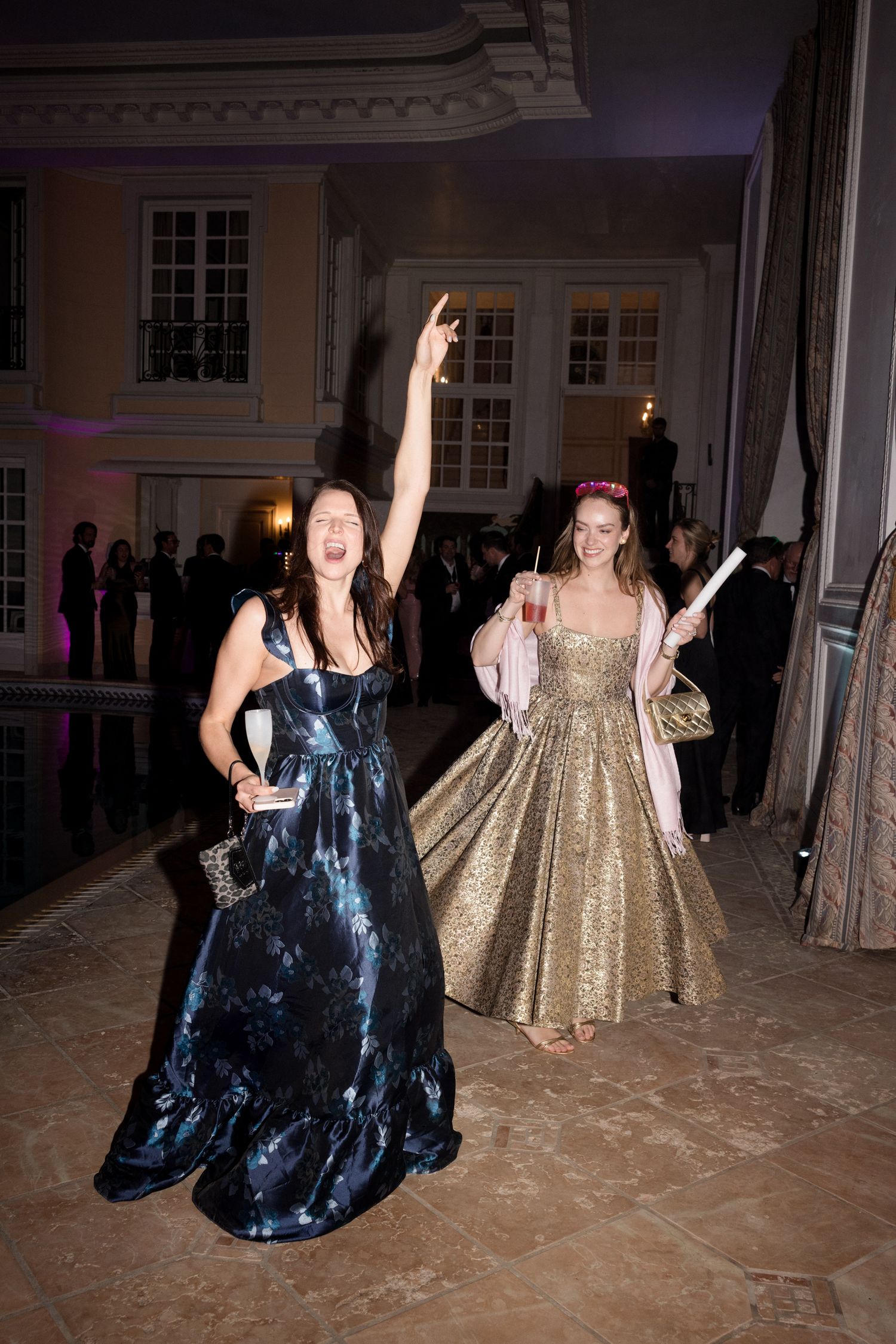 Two people dancing in formal dresses at an elegant ballroom event with ornate decor. Photographe mariage france luxe