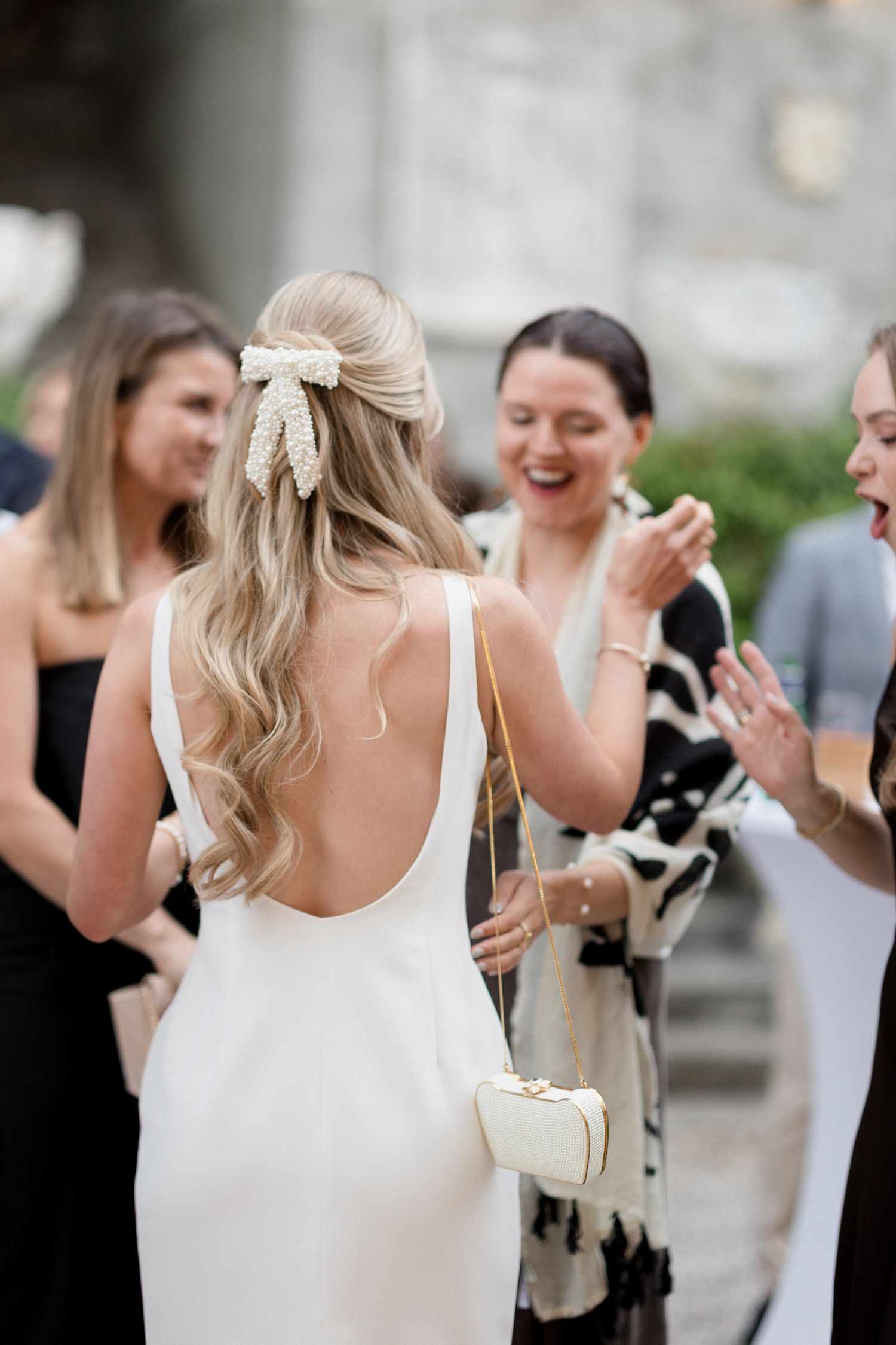A group of wedding guests laugh and smile together during an outdoor celebration.
