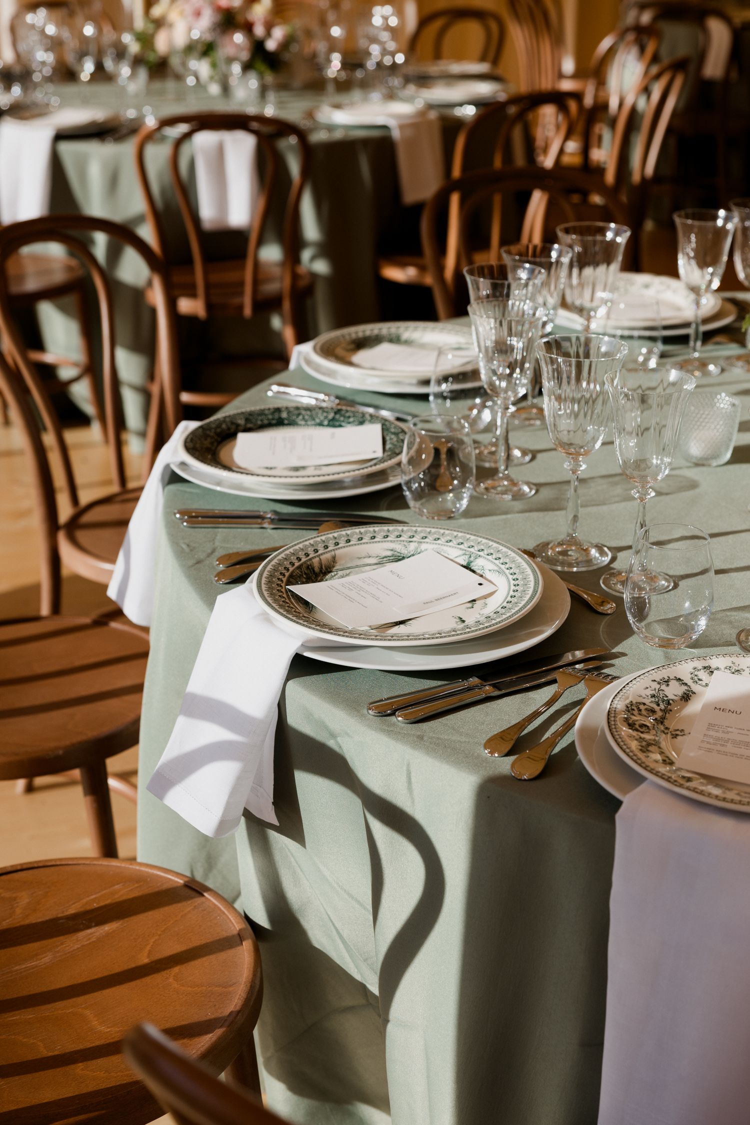 Elegant table settings with mint green linens and vintage plates arranged for a formal dining event.
