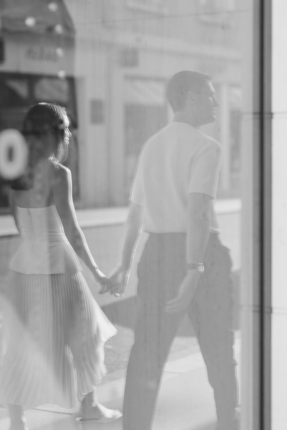 A blurred monochromatic scene of people walking through what appears to be a shopping area.