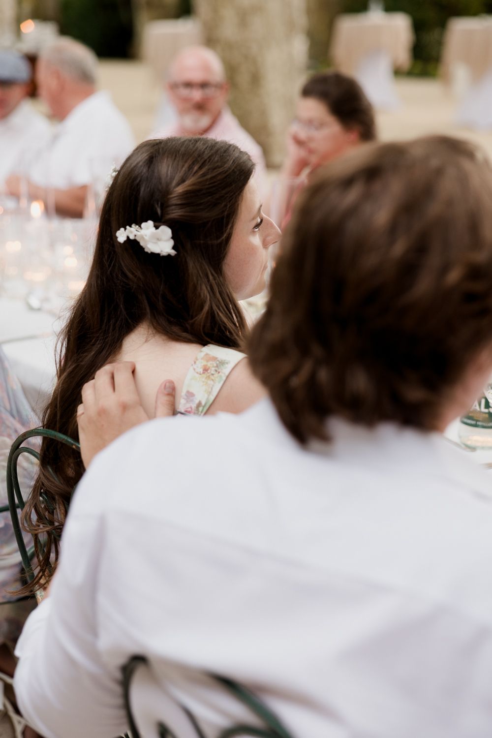 Guest wearing a delicate floral hair accessory during an elegant outdoor dinner reception.