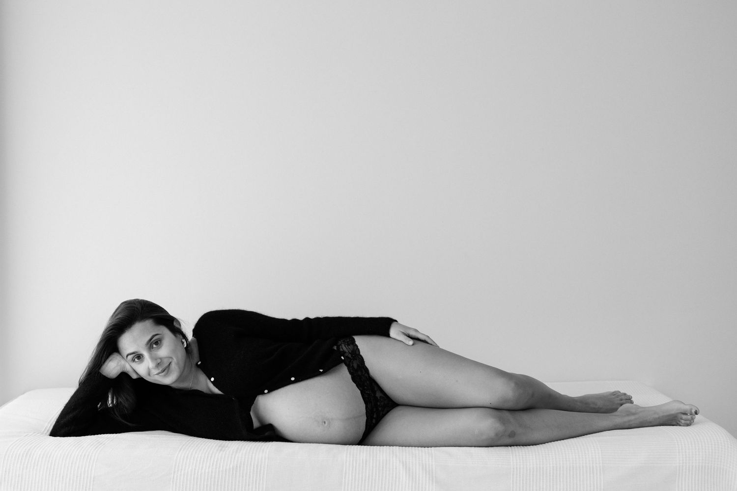 A black and white artistic photo series shows a person lying down in different poses against a light background.