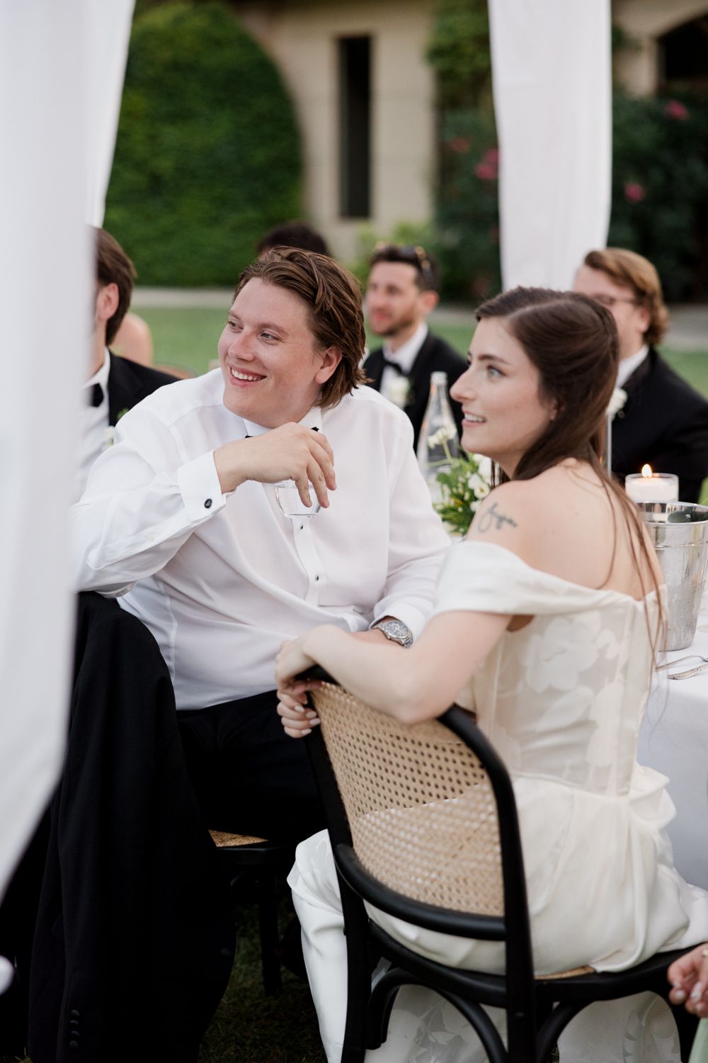 A sequence of wedding reception photos showing a couple leaning back and laughing while seated in chairs outdoors.