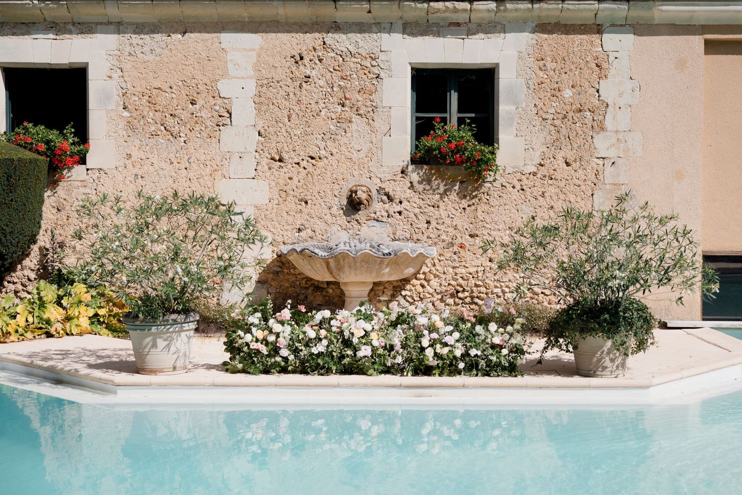 Decorative stone walls and architectural details with pink hues and flowering plants create a Mediterranean ambiance.