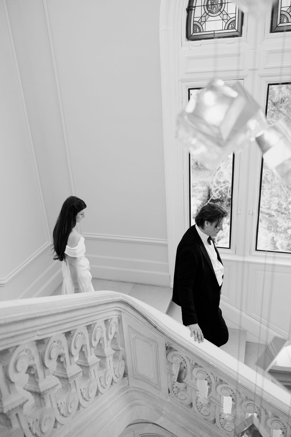 A sequence of artistic black and white photos showing a person ascending an ornate staircase with white decorative railings.
