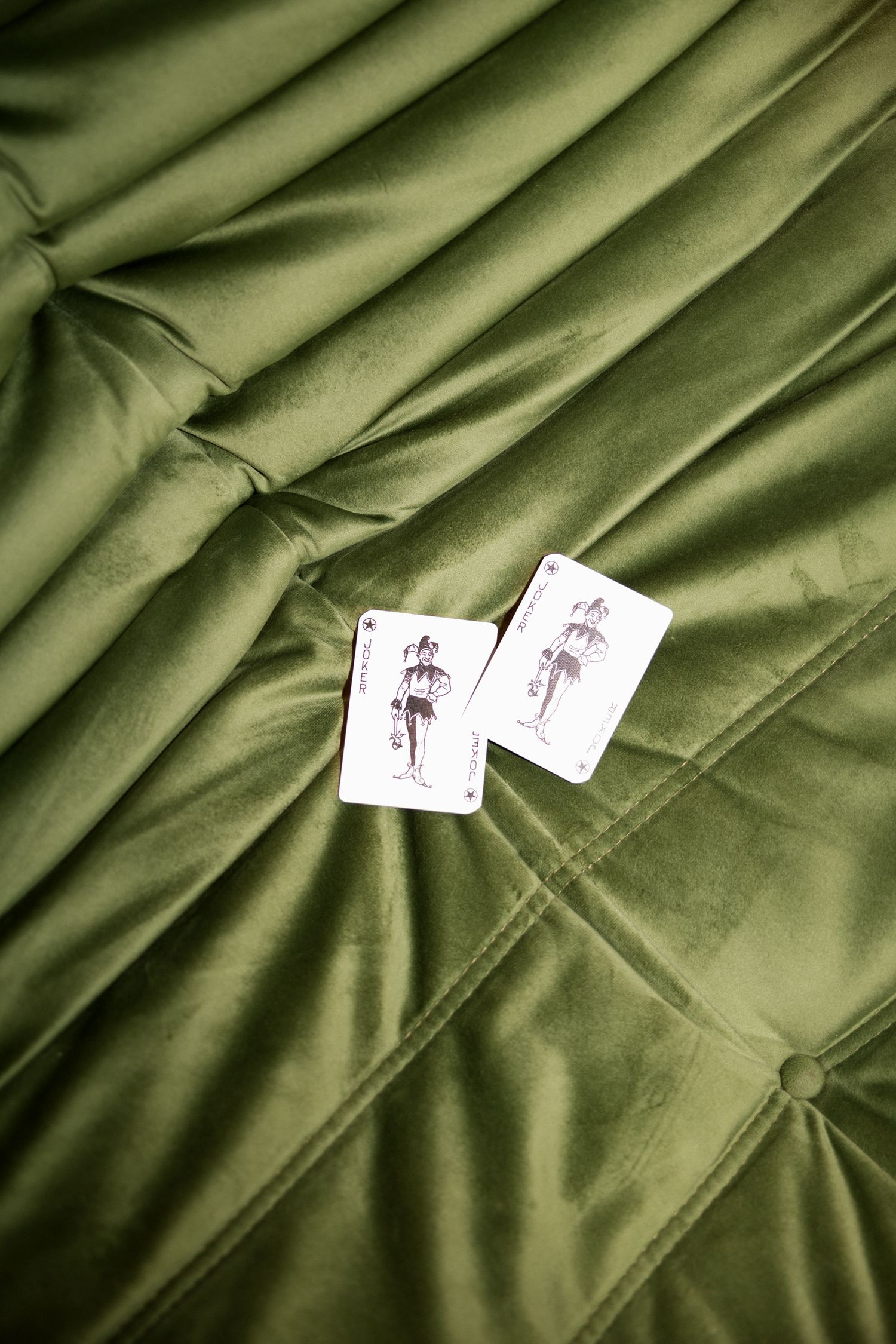 Close-up view of green satin fabric with white clothing tags showing textural details and folds. wedding photographer france