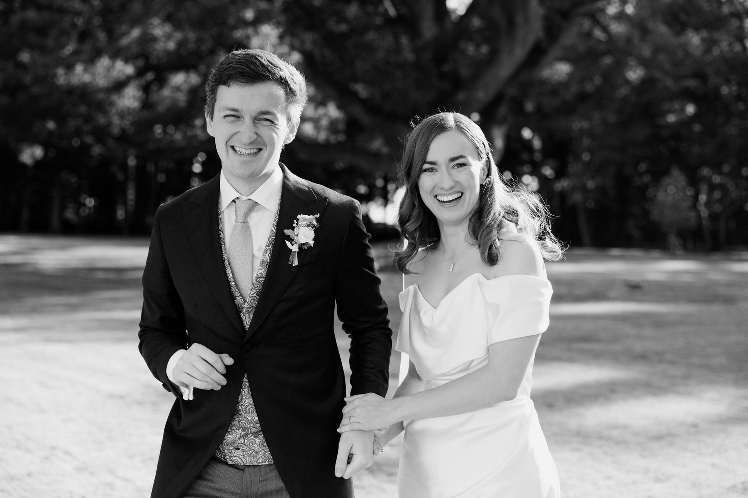 A black and white wedding photo series showing candid moments of a couple walking and embracing outdoors.