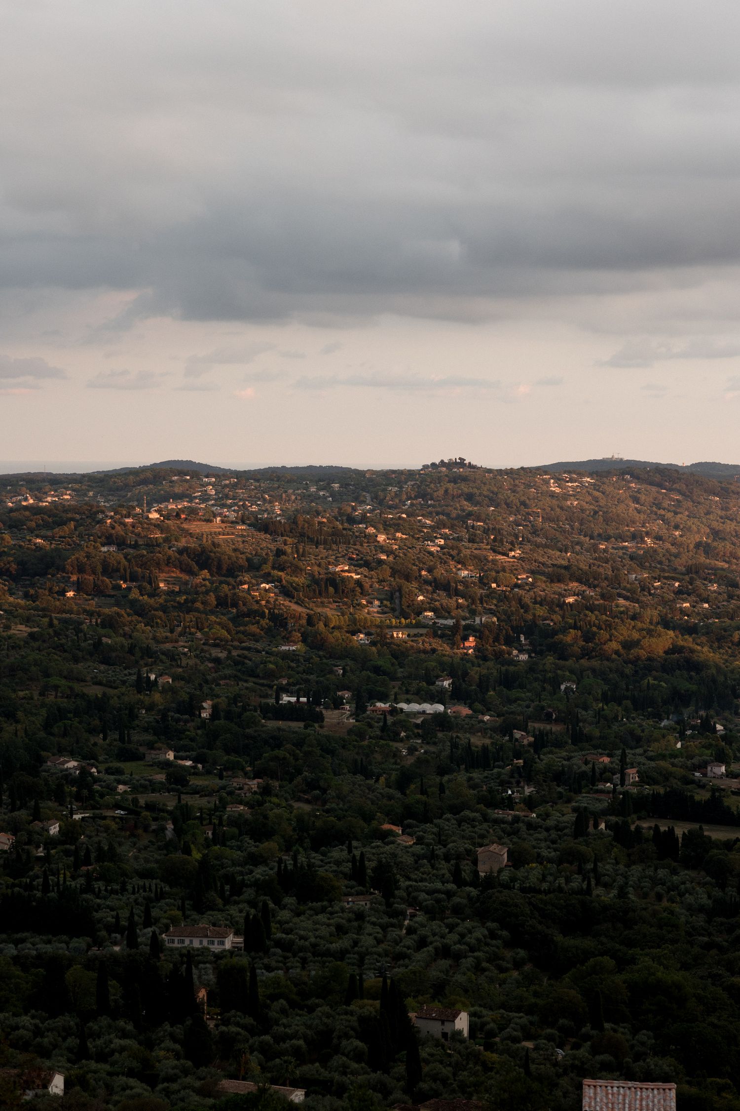 Panoramic view of hillside homes nestled among trees in a mountainous landscape at sunset. destination wedding france provence