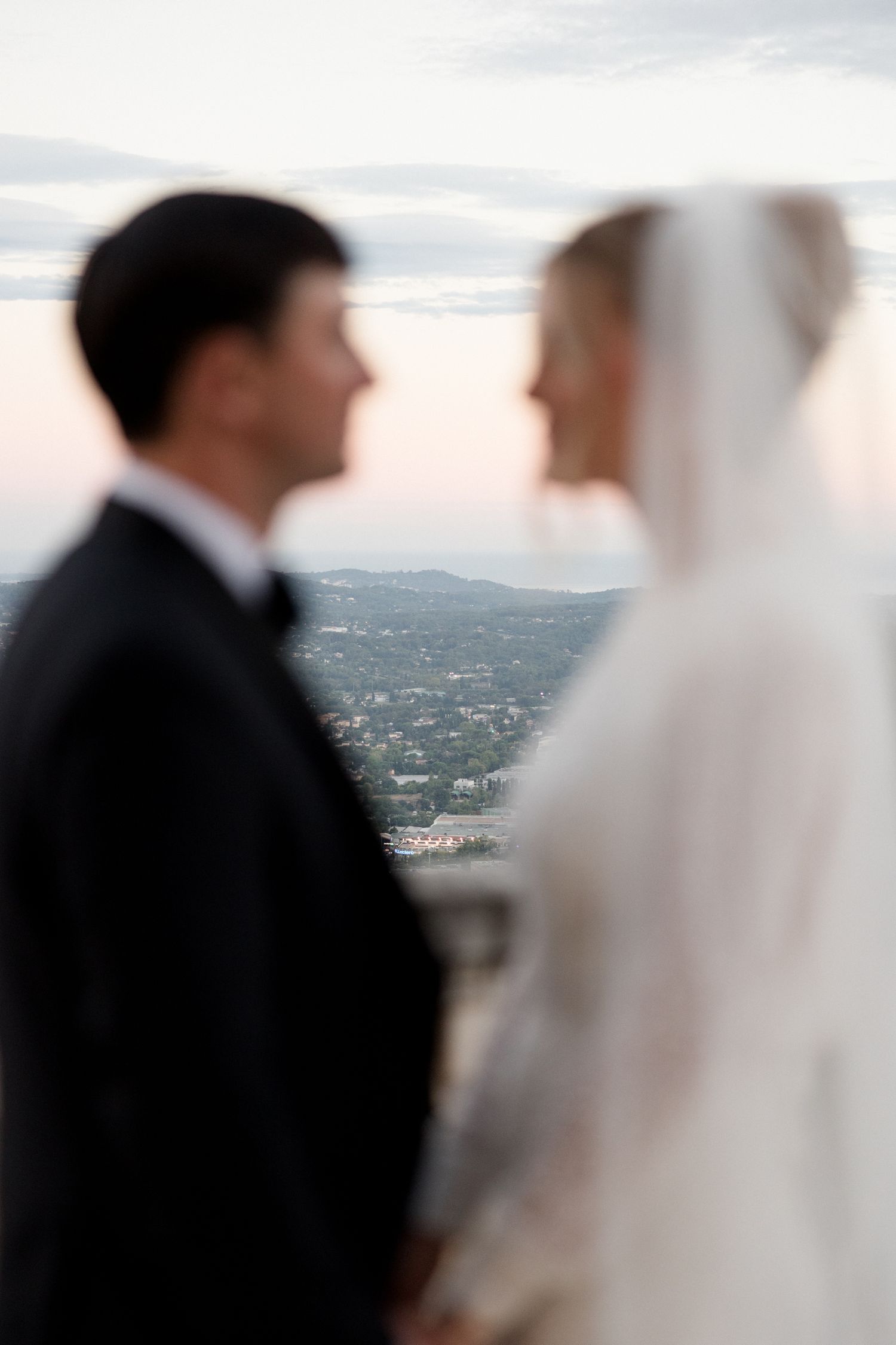 A bride and groom share an intimate moment overlooking a scenic mountain vista during their wedding ceremony. Mariage Chateau saint georges