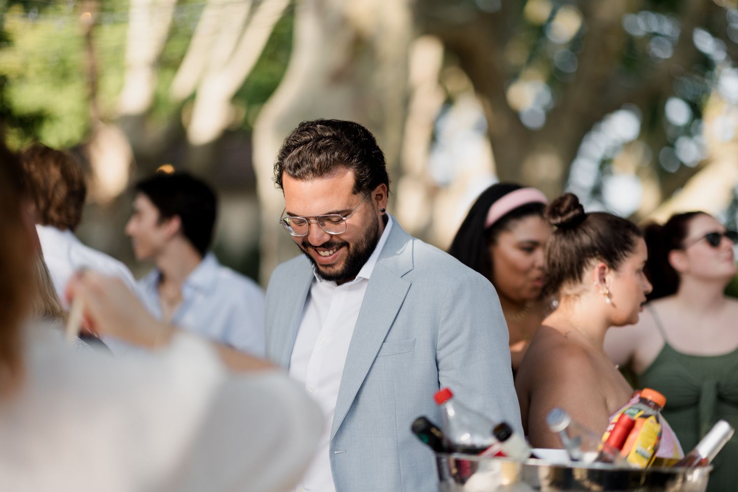 A candid moment at an outdoor wedding reception shows guests socializing and laughing together.