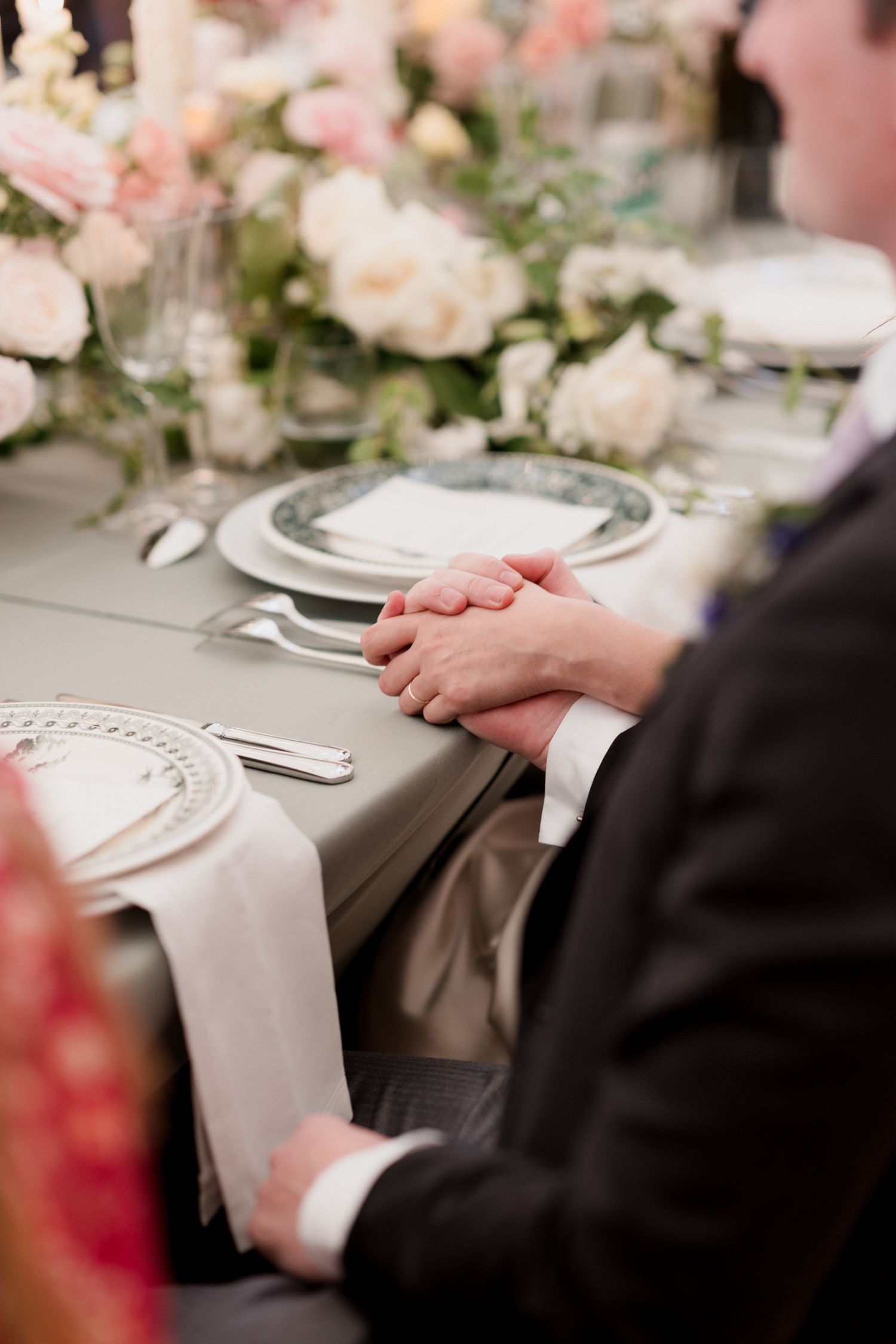Elegant wedding table setting with white linens and delicate floral arrangements at a formal reception.