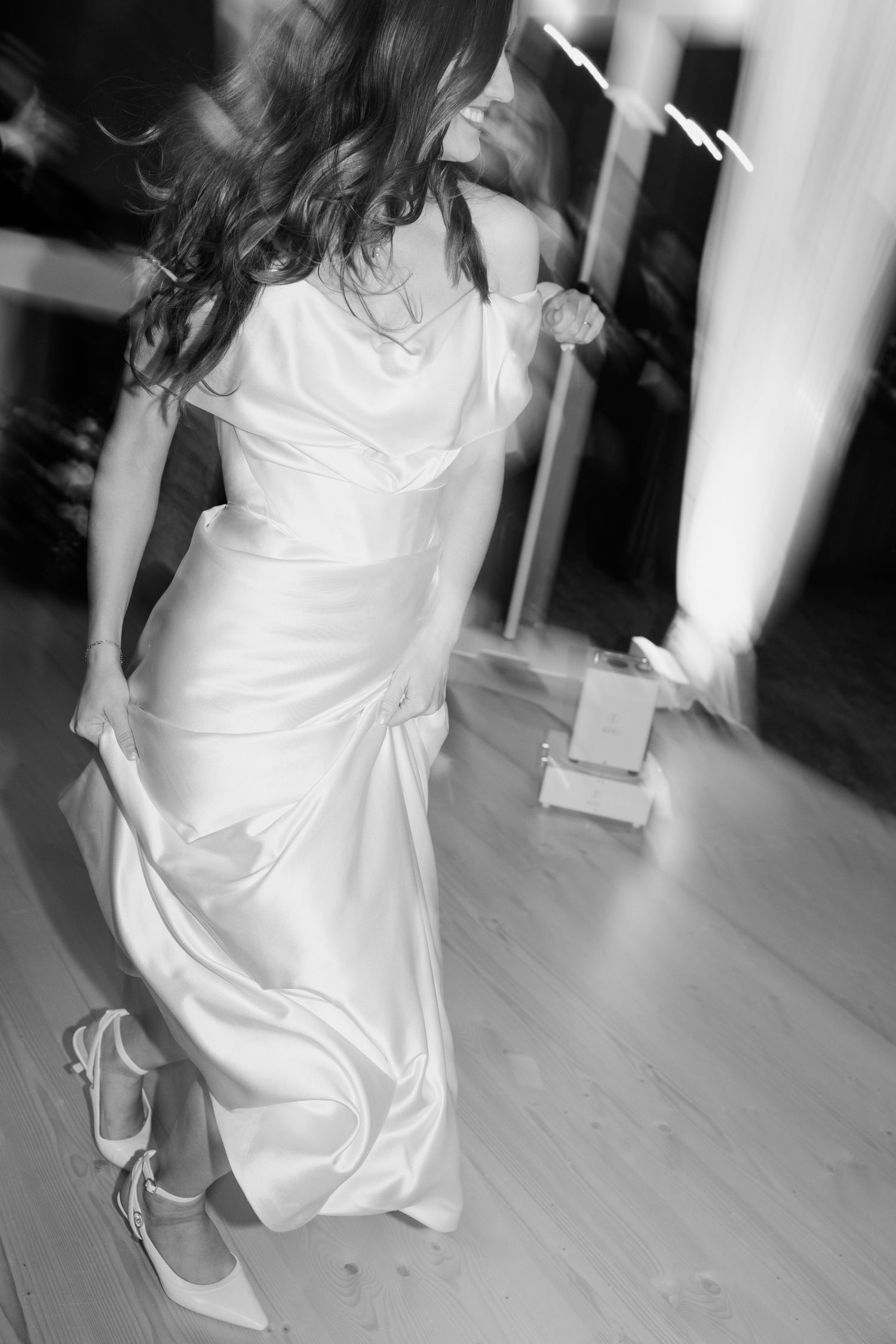 Black and white sequence shows a bride in a flowing white dress dancing and twirling on a wooden floor.