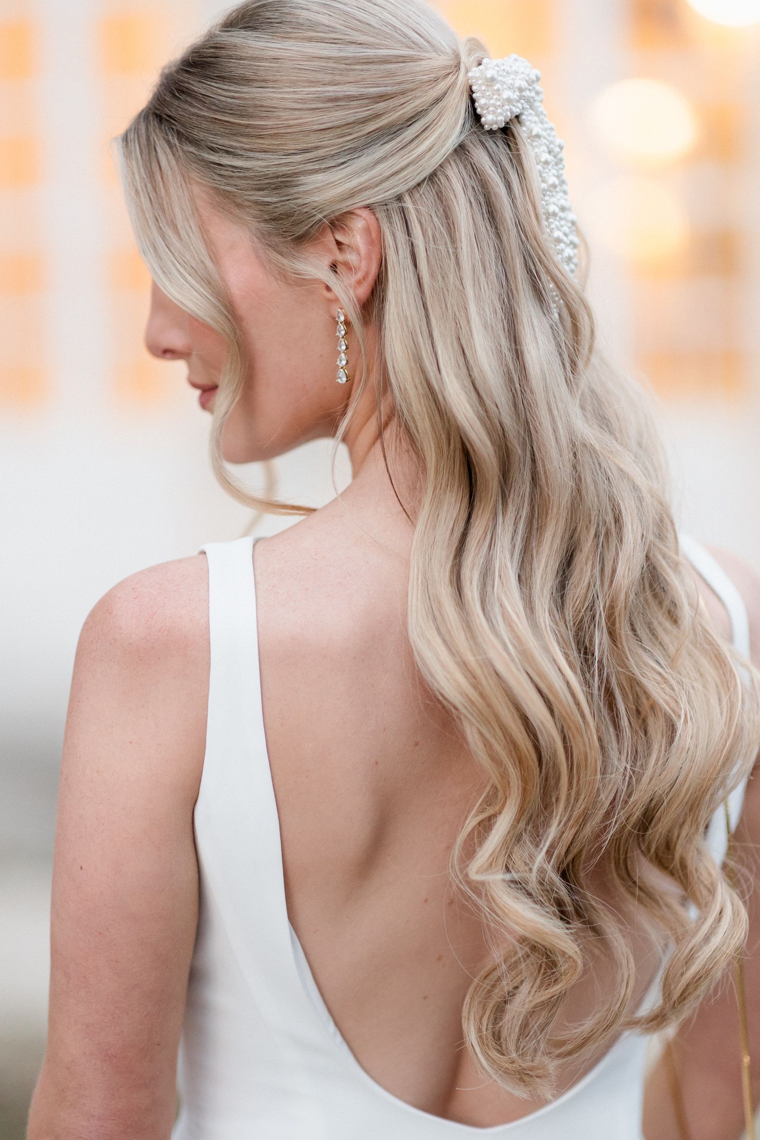 Elegant bridal hairstyle featuring soft blonde waves and a sparkling crystal hair accessory for a wedding day look. chateau saint georges