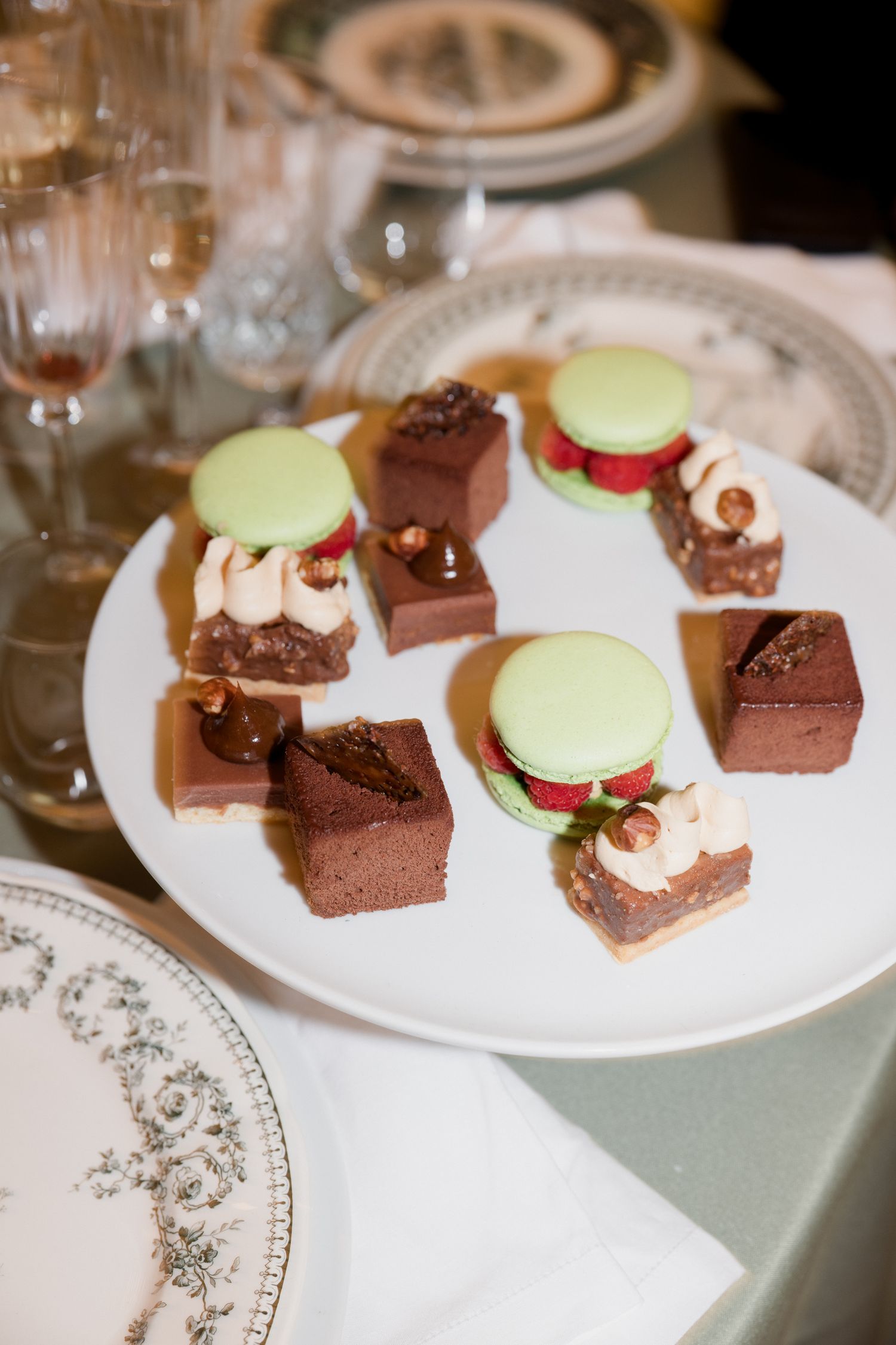 Elegant dessert plates featuring chocolate squares and delicate pastries with pale green garnishes.