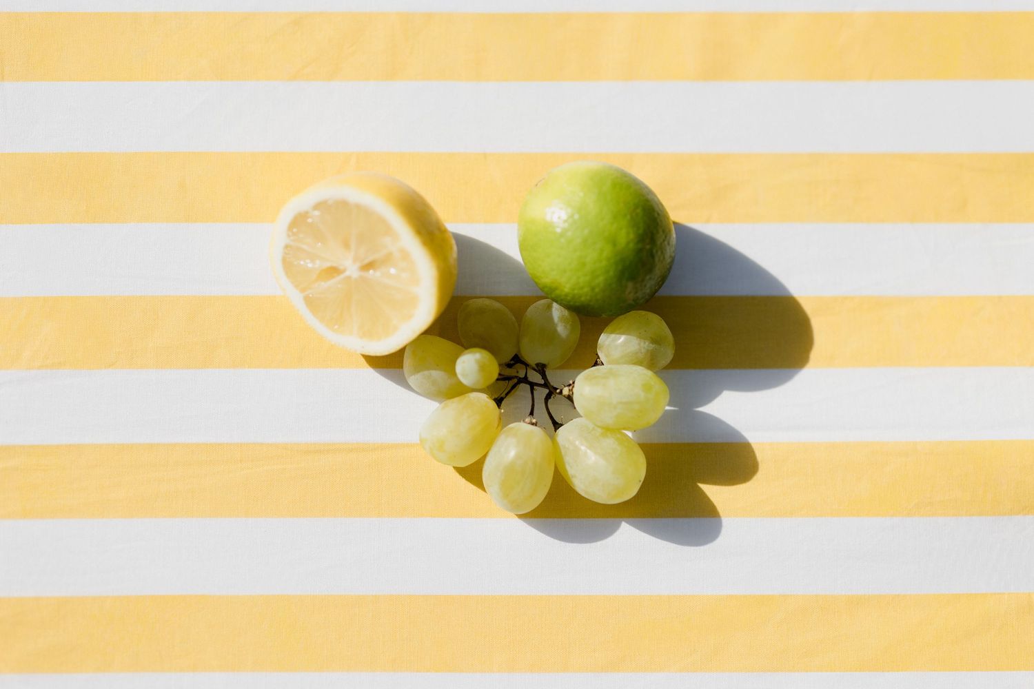 Fresh citrus fruits and grapes arranged in a repeating pattern on orange and white striped background. Paris wedding photographer
