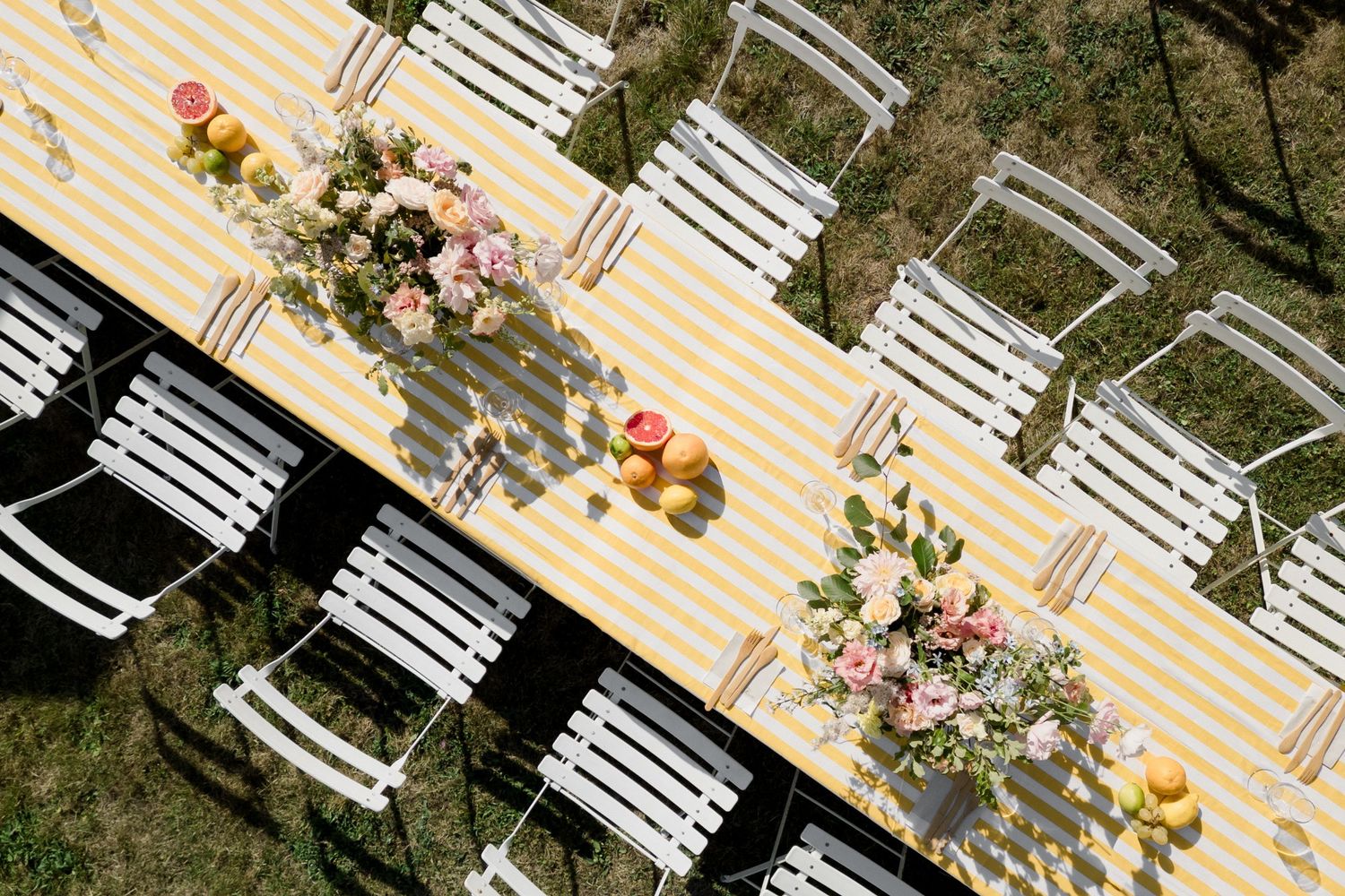White wooden chairs arranged in rows on a striped floor with pink flowers decorating the outdoor event space. Paris wedding photographer