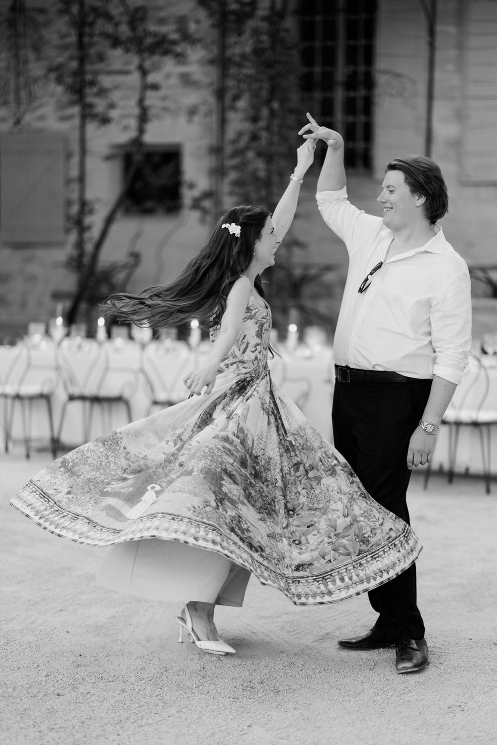 A couple dances together outdoors in black and white, with the woman's patterned dress twirling elegantly during their dance.