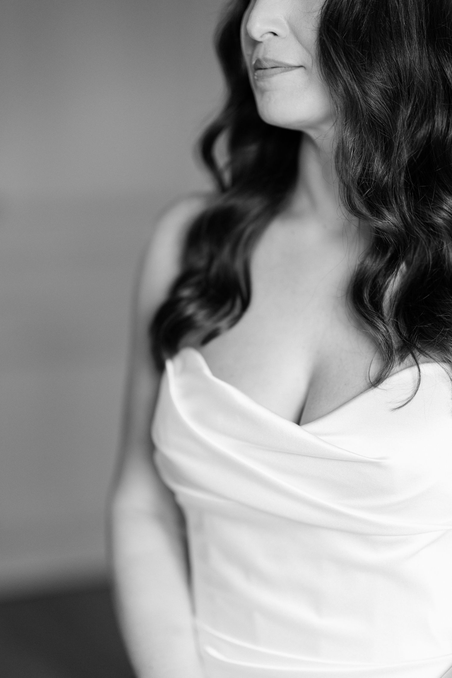 Black and white portrait showing the elegant draping of a white dress against a soft background.