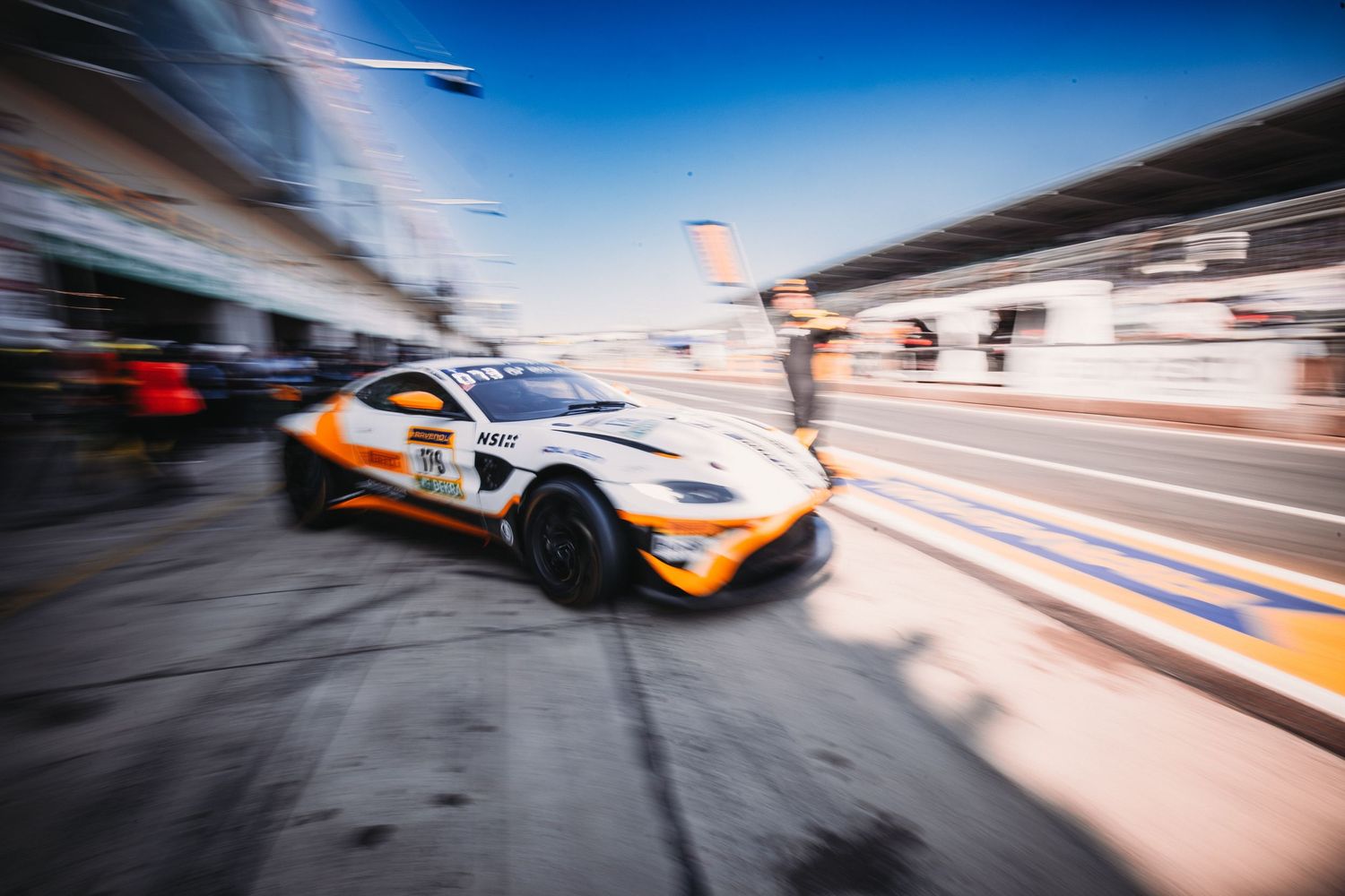 Formula One race cars speed past with motion blur on a racetrack during high-speed competition.