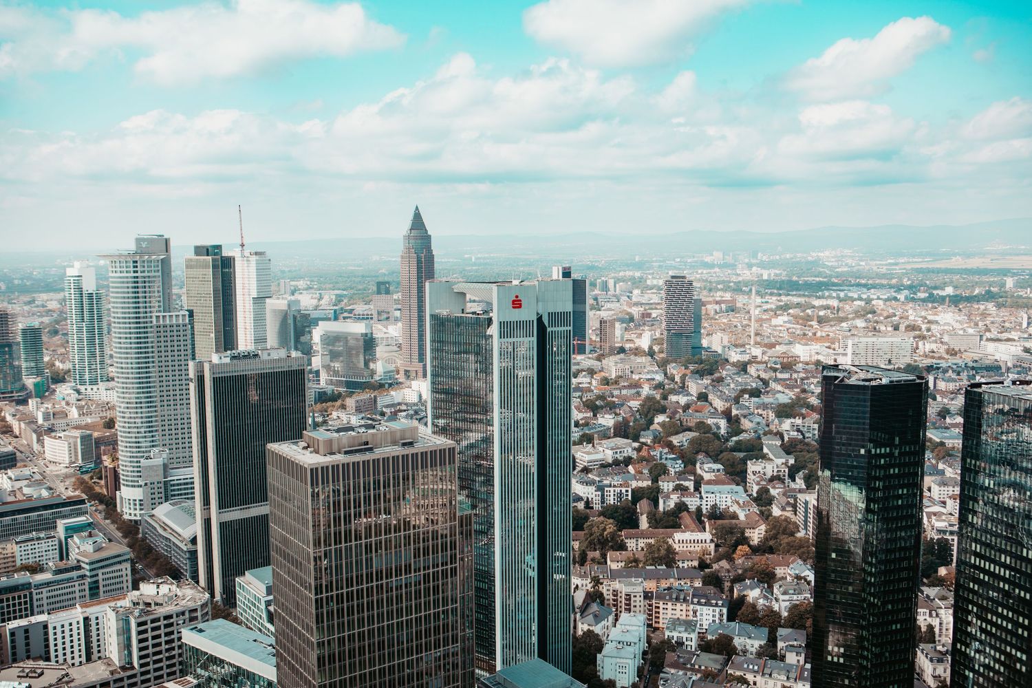 Panoramic aerial view of modern skyscrapers and urban cityscape with glass buildings against cloudy sky in daylight.