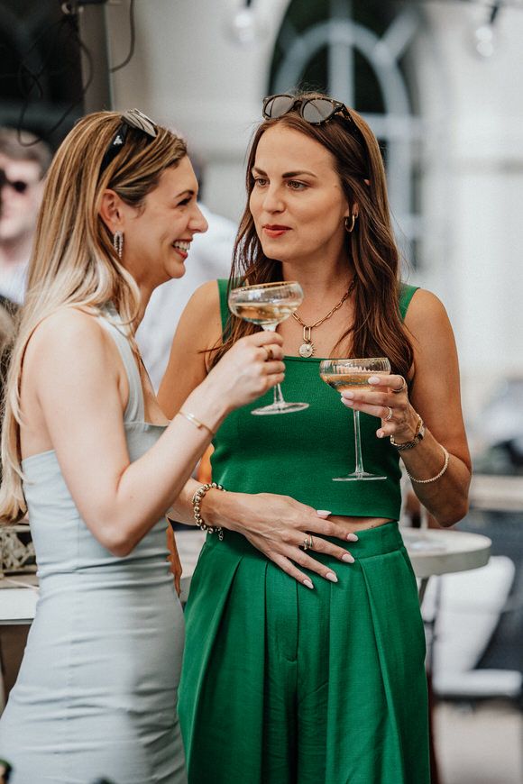 Hochzeitsgäste in grünen und grauen Kleidern stoßen mit Champagner an – stilvoll heiraten im Morrhof.