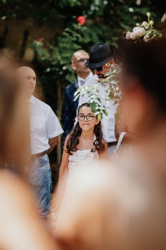 A wedding celebration in an outdoor garden setting with guests gathered around during a sunny day.