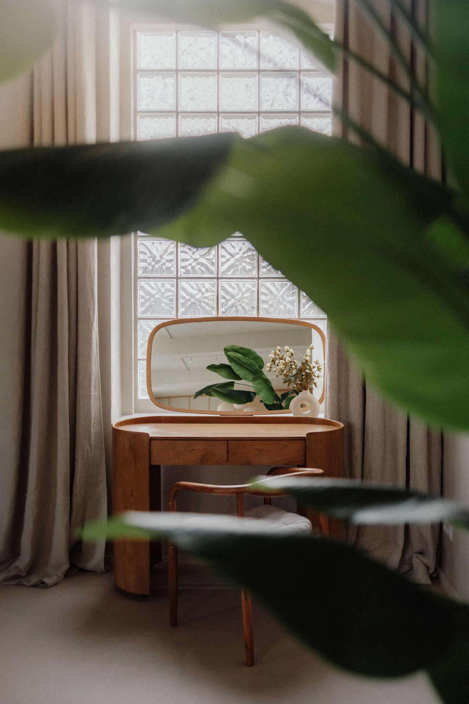 Mid-Century-Holzfrisiertisch mit Spiegel am Fenster, umgeben von grünen Pflanzen – Business Shooting Frankfurt