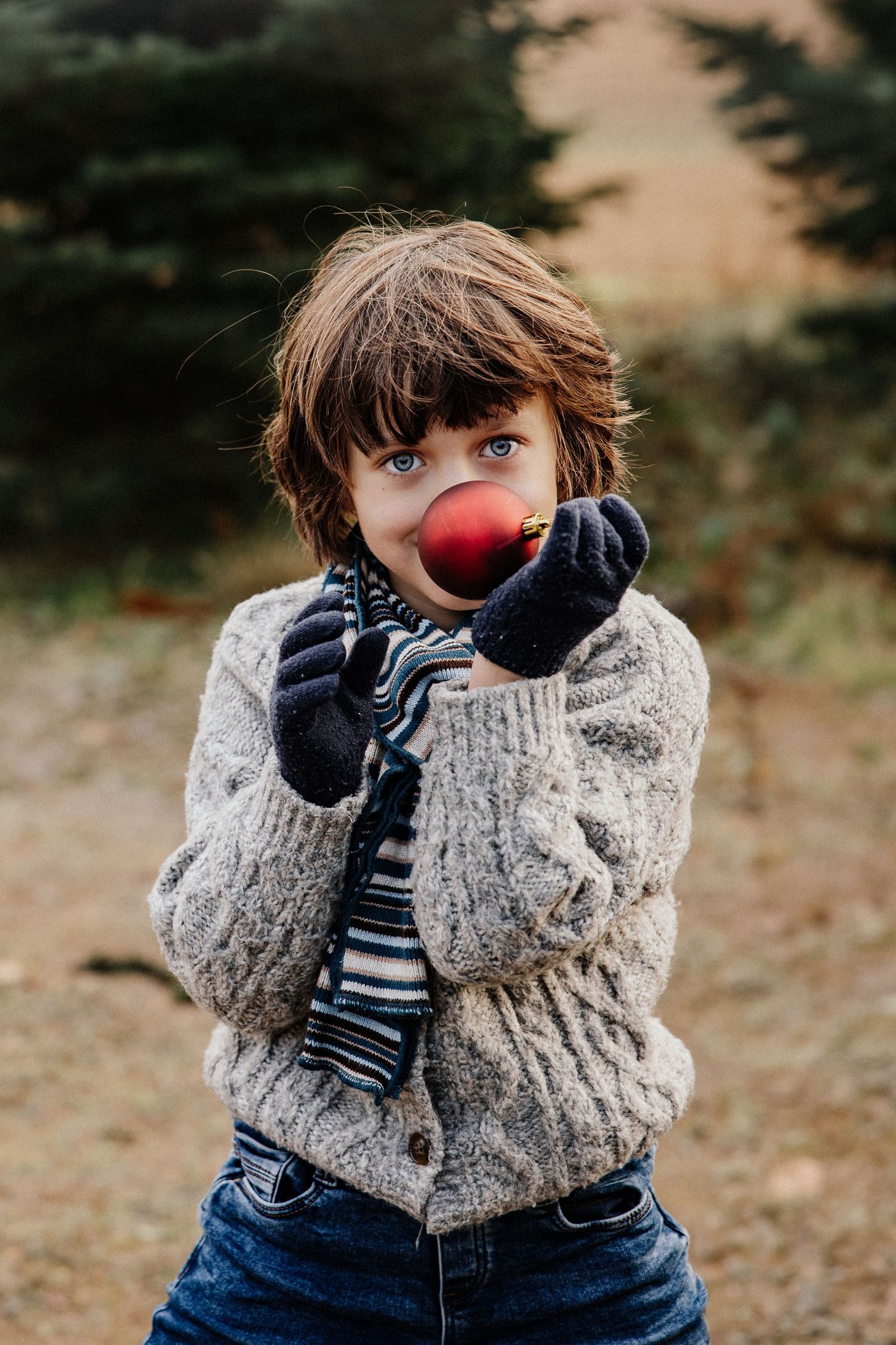 A series of photos showing a child in a knit sweater and gloves eating a red apple outdoors in autumn.