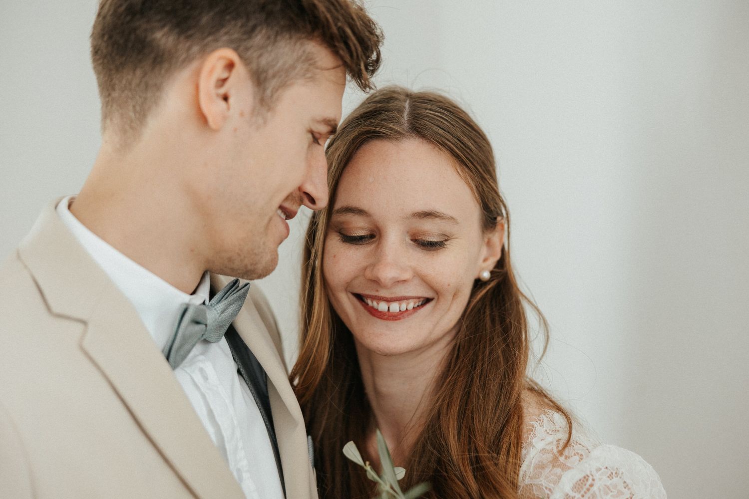 Tender moment between couple in light-filled room with neutral tones and minimal styling.