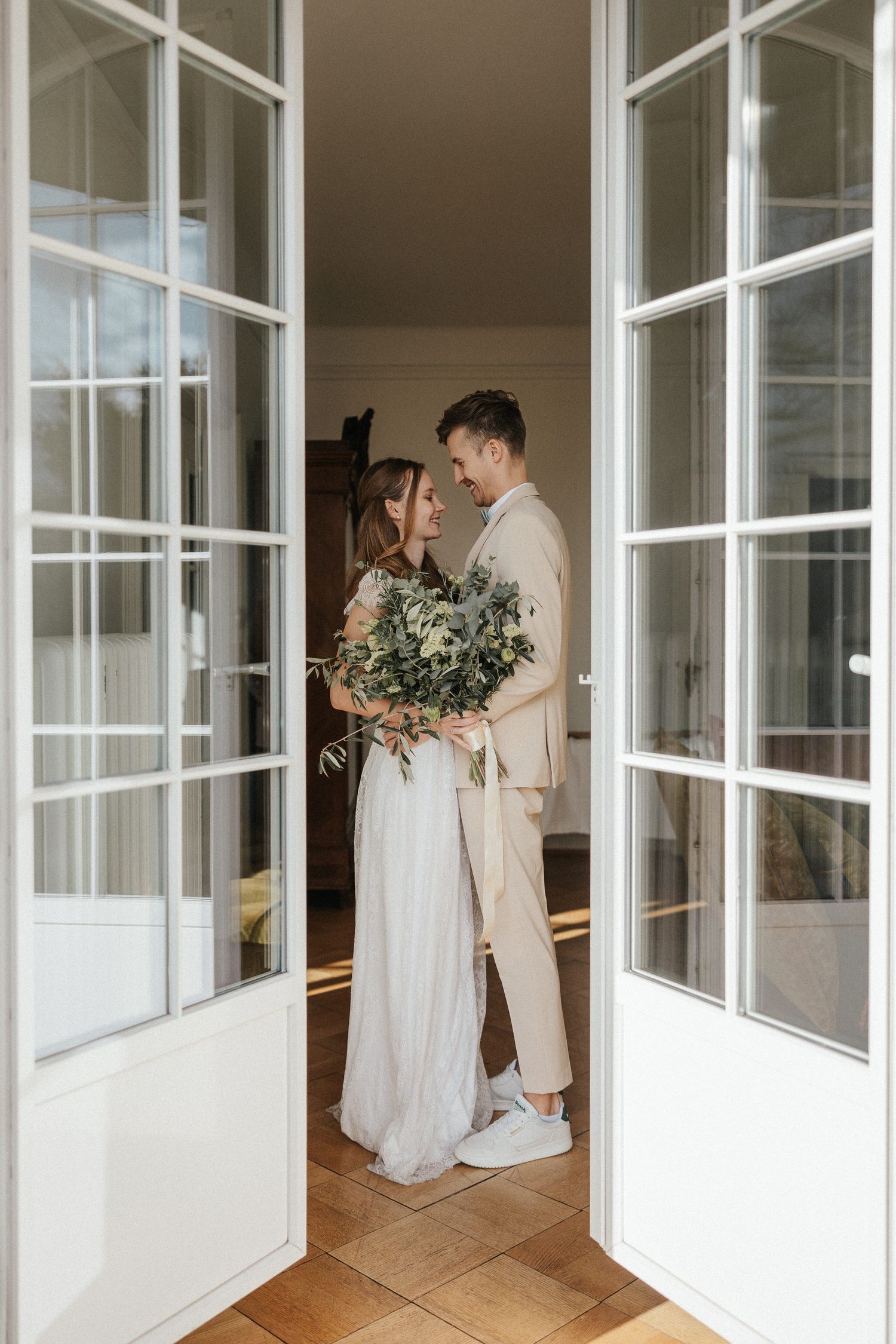 Intimate wedding photos through window panes in bright interior space.
