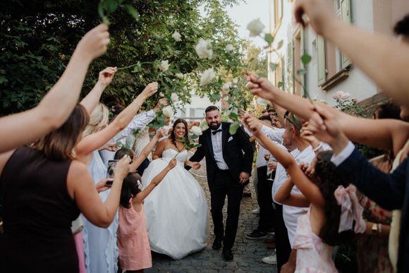 Hochzeitsfotograf Boudier & Koeller – Gäste bilden draußen einen Tunnel mit erhobenen Armen bei Feier.